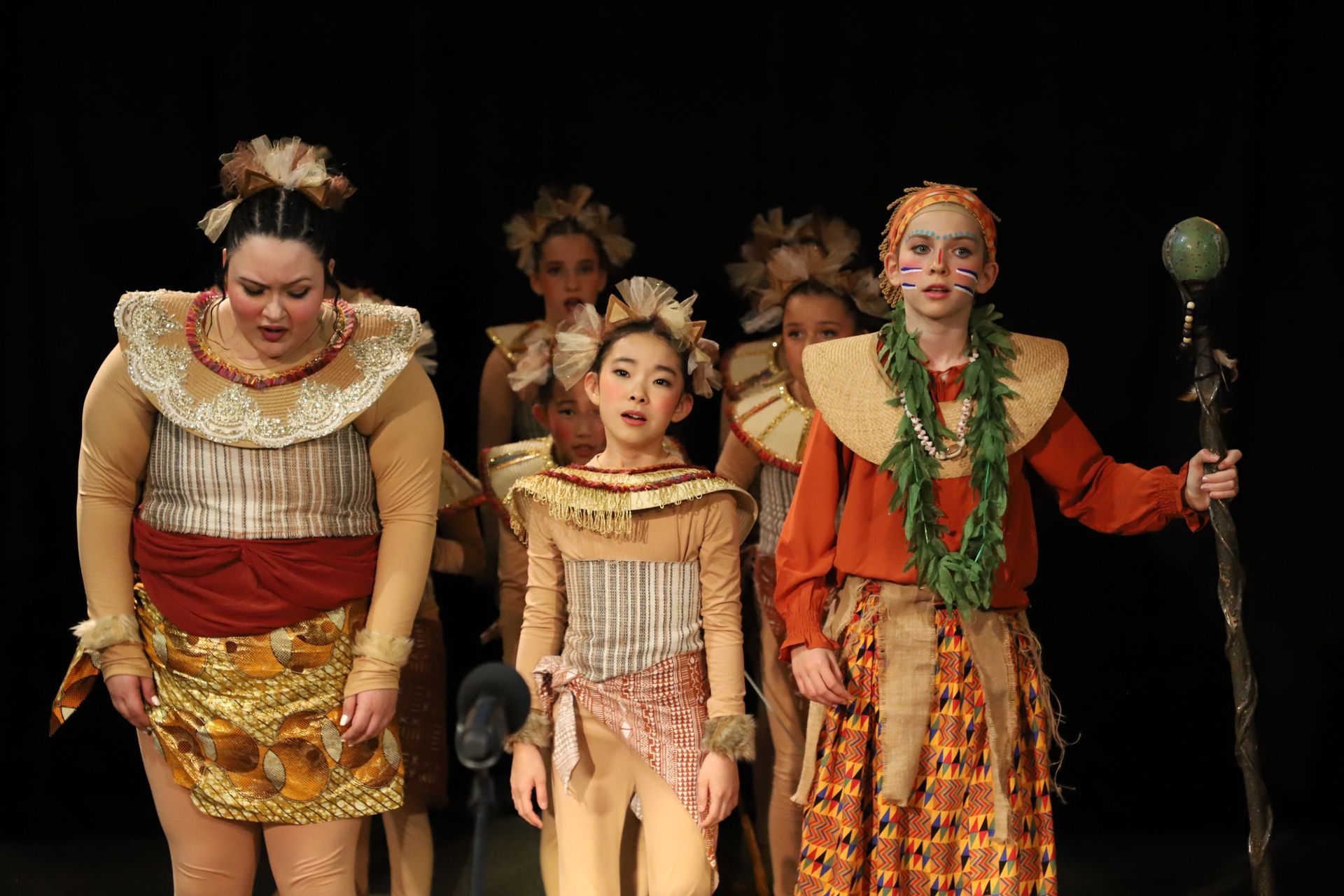A group of people dressed in costumes are standing on a stage.