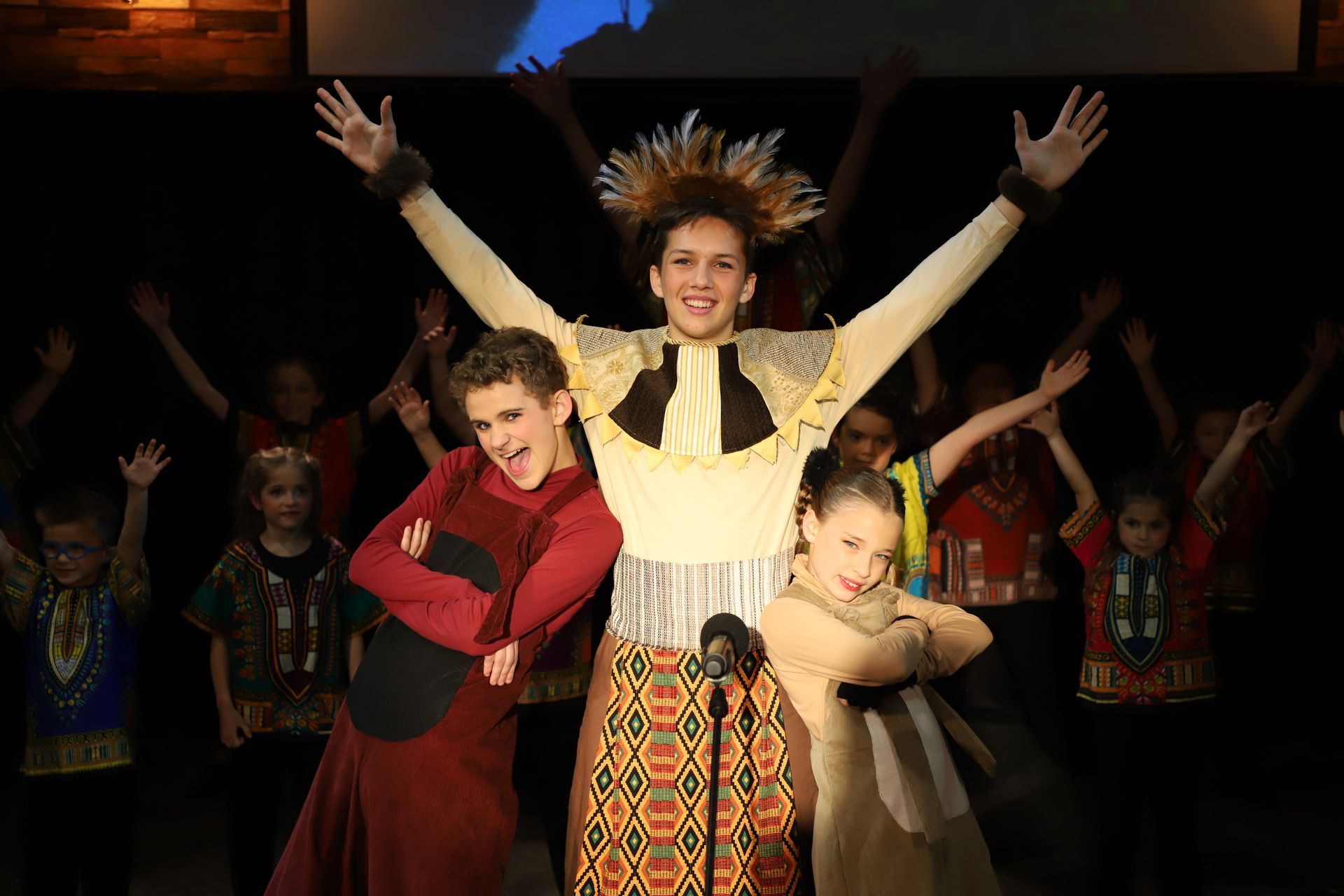 A group of children are standing in front of a microphone on a stage.