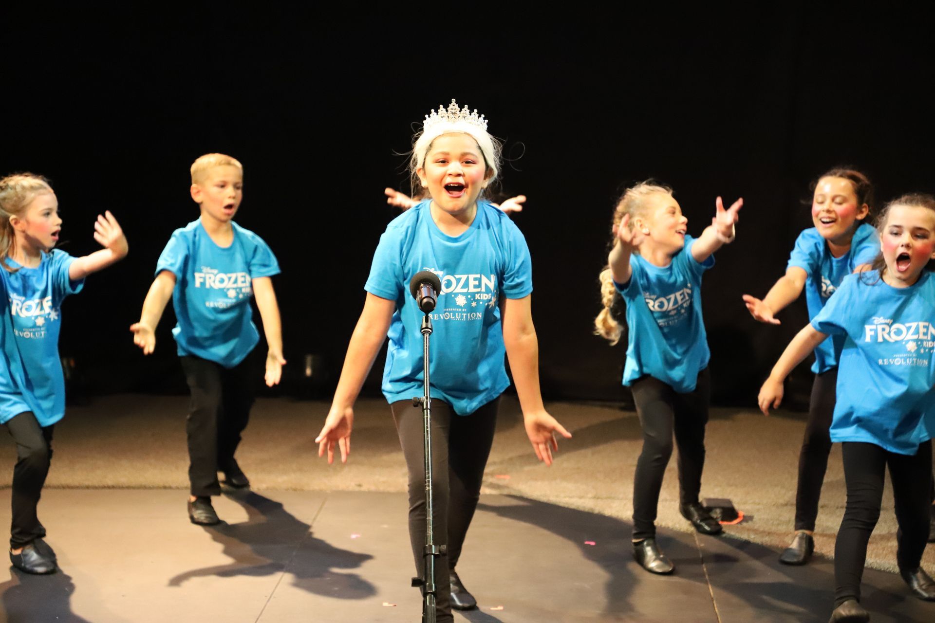 A group of young children are dancing on a stage.