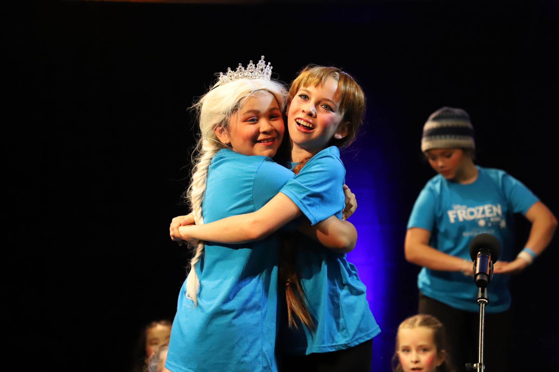 A boy and a girl are hugging each other on a stage.