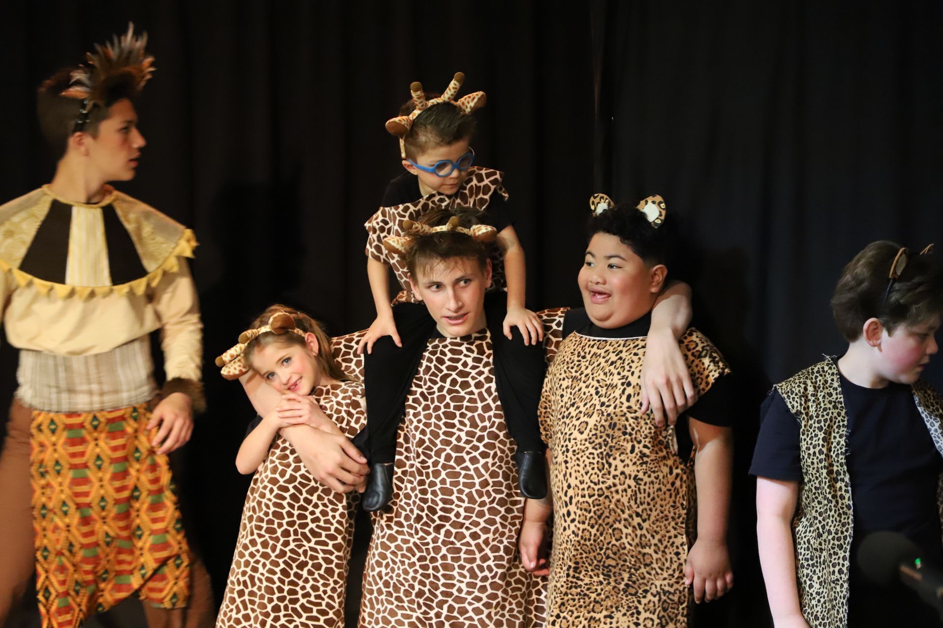 A group of children dressed in leopard print costumes are posing for a picture.
