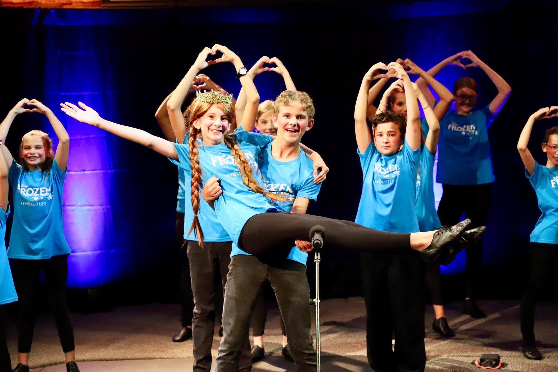 A group of young people are making hearts with their hands on a stage.