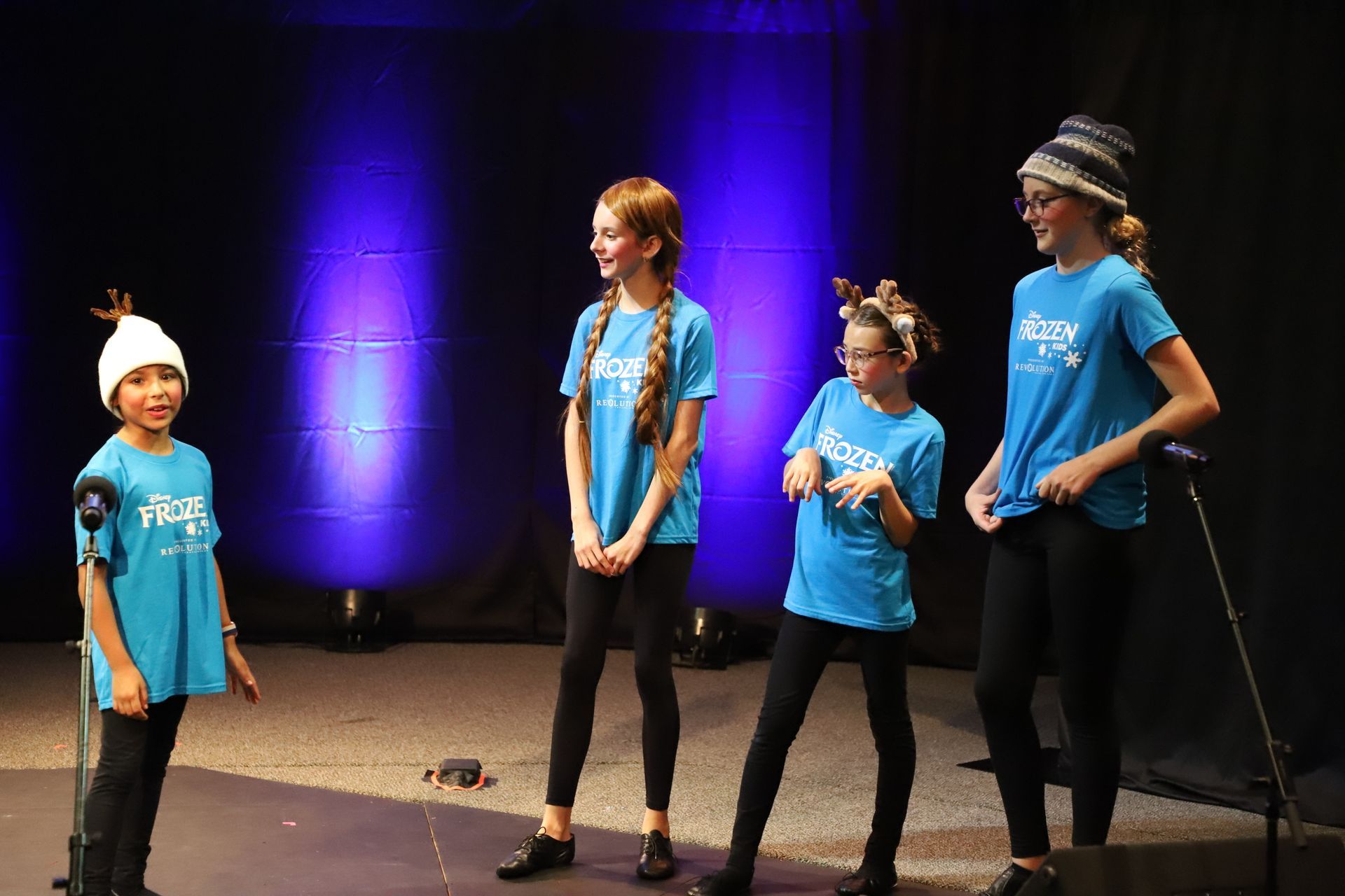 A group of young girls are singing into microphones on a stage.