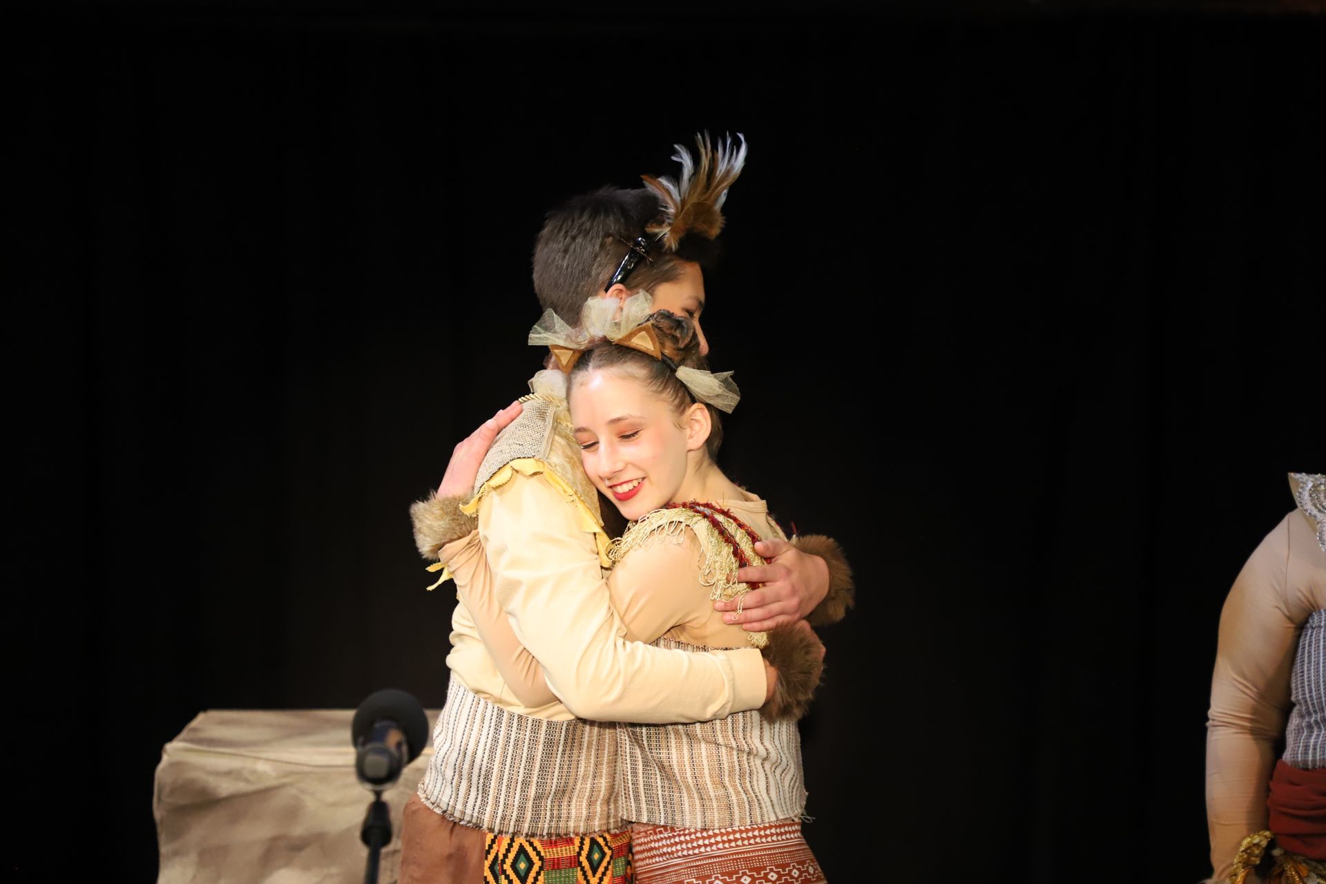 A man and a woman are hugging each other on a stage.