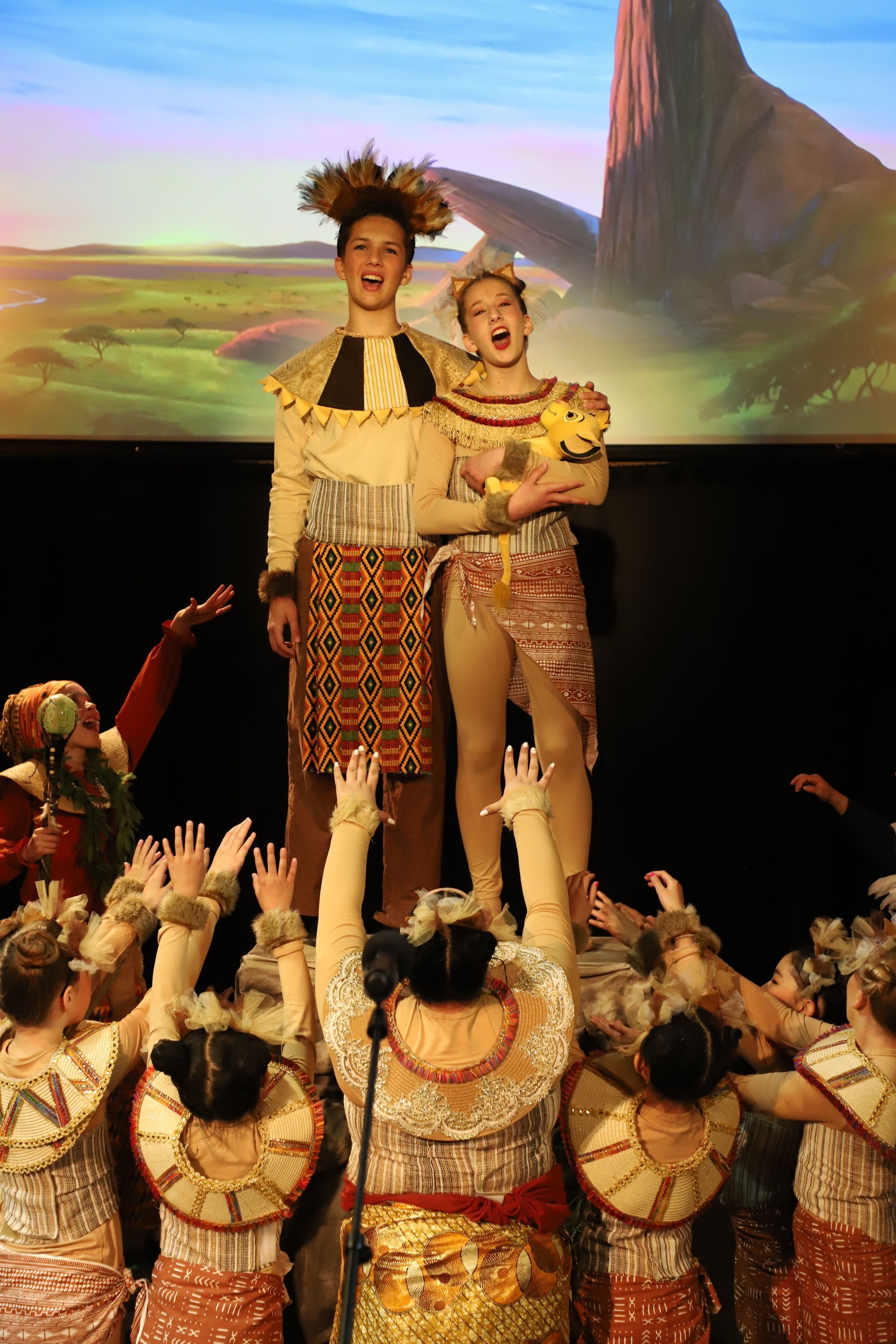 A group of people are standing on a stage with their hands in the air.