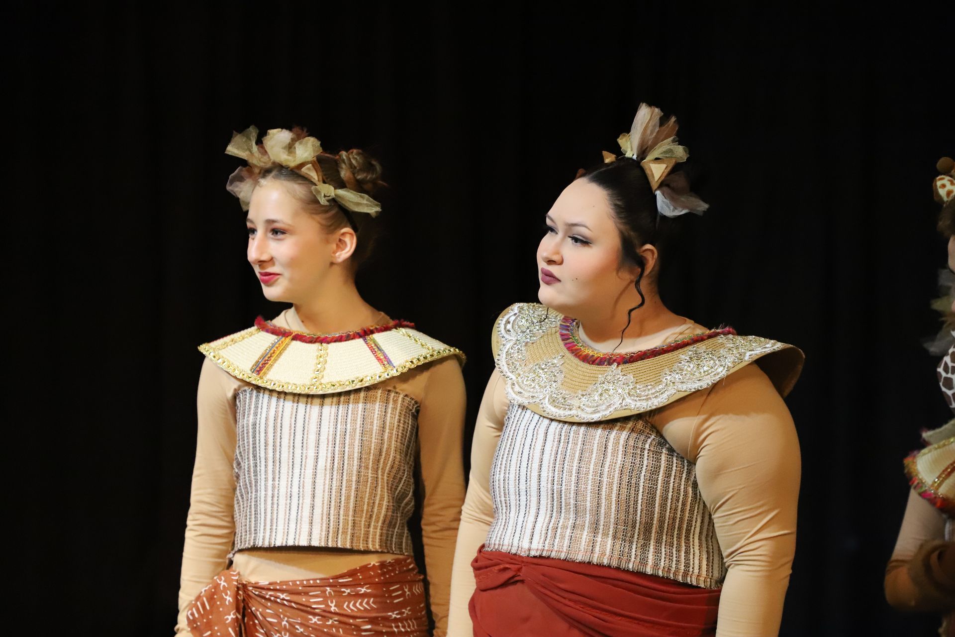 Two women in costumes are standing next to each other on a stage.