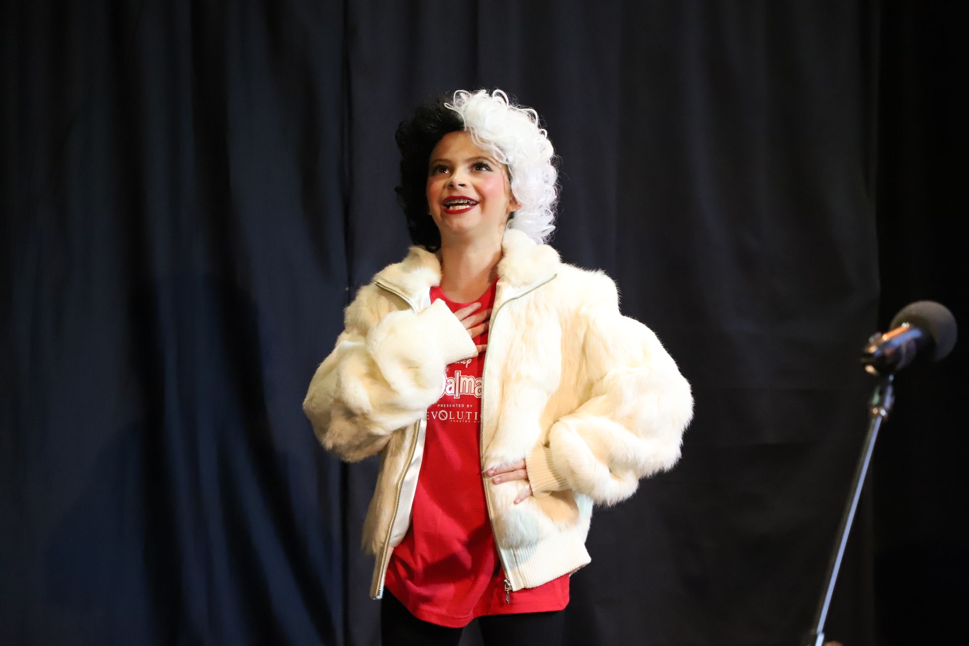 A woman in a fur coat is standing in front of a microphone.