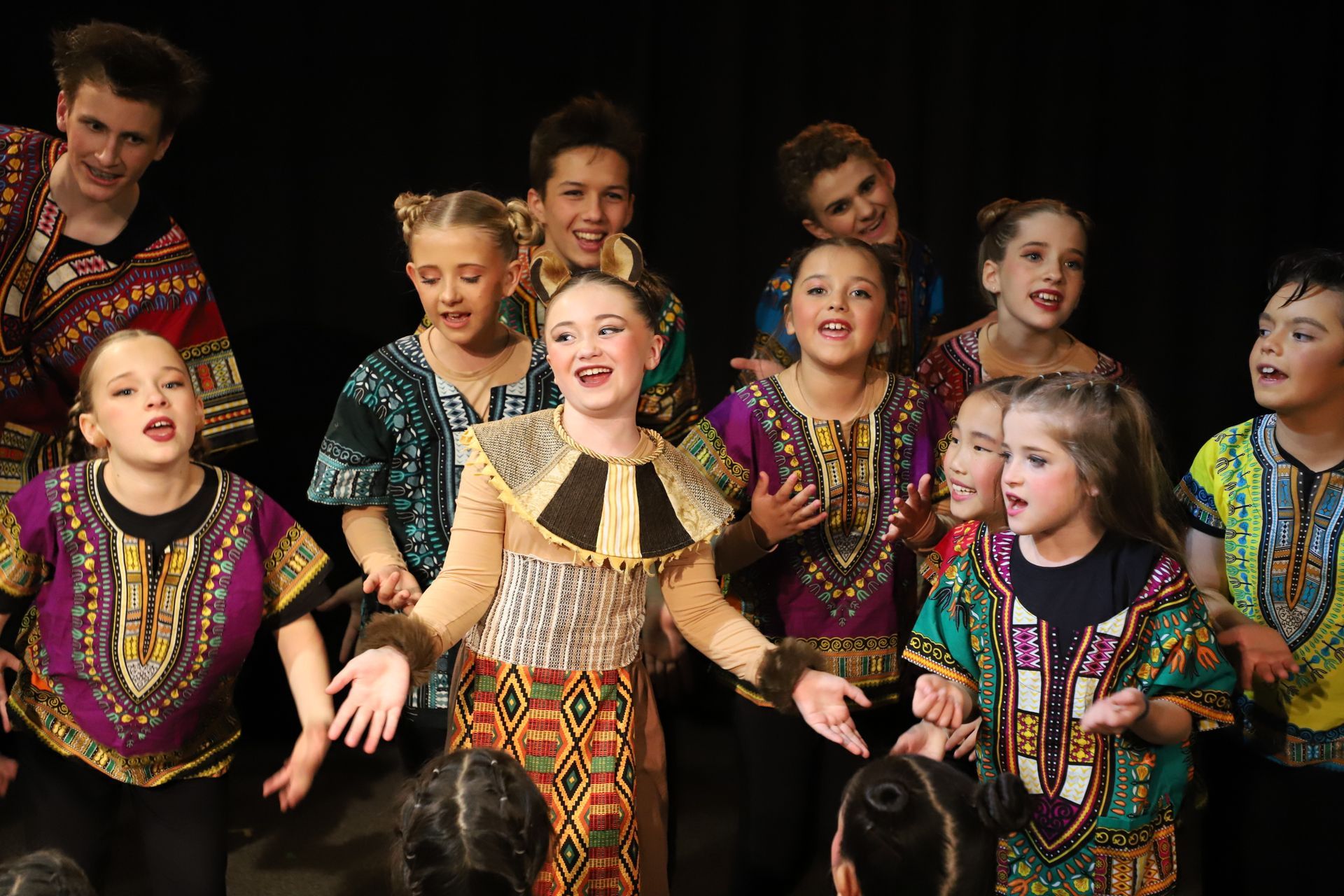 A group of children are standing next to each other on a stage.