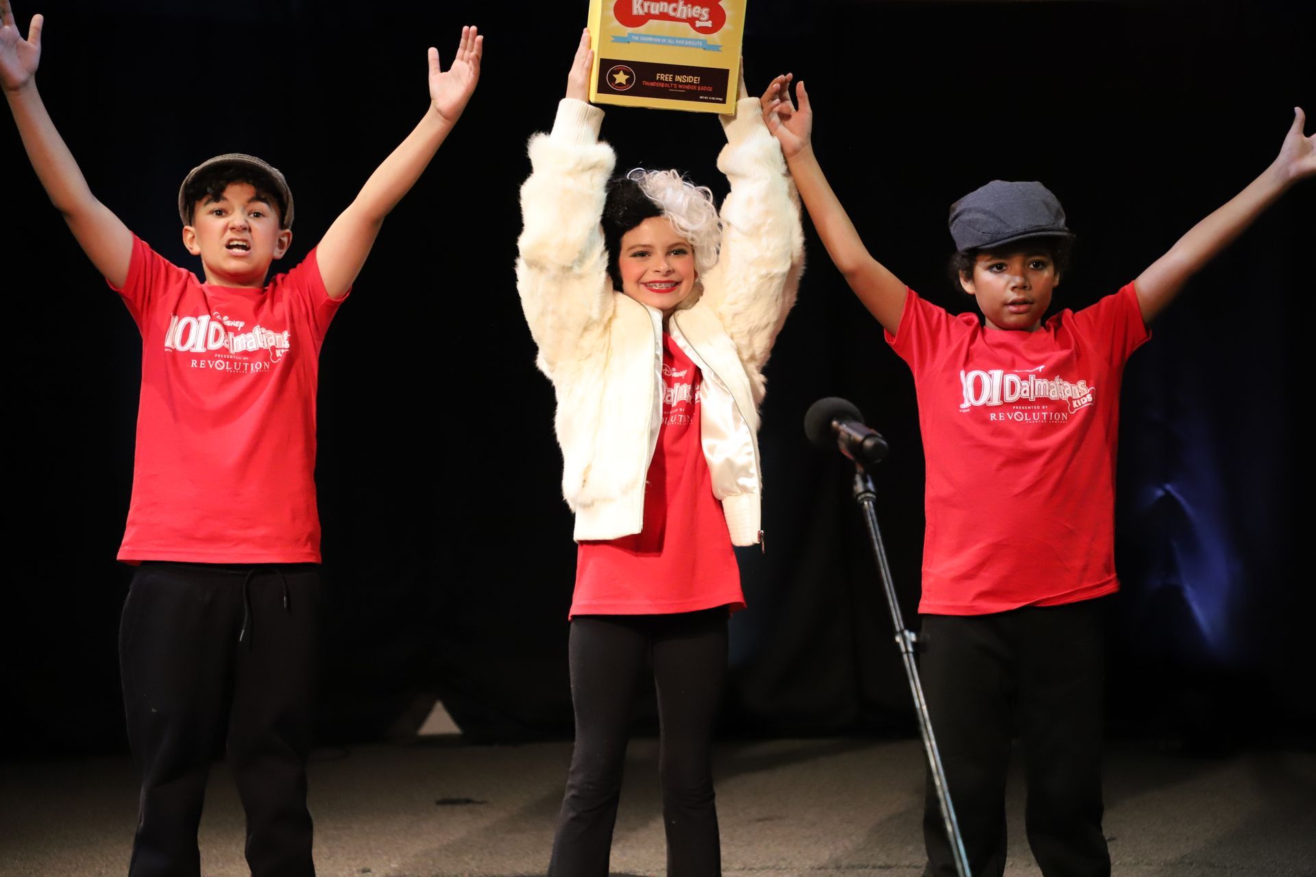 Three children in red shirts are holding up a trophy