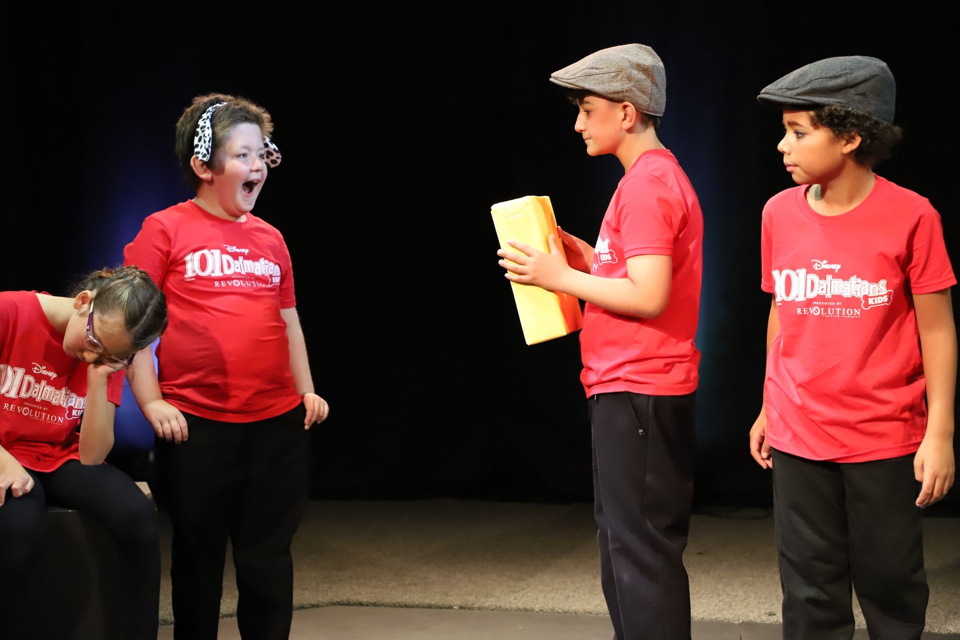 A group of children in red shirts are standing on a stage.