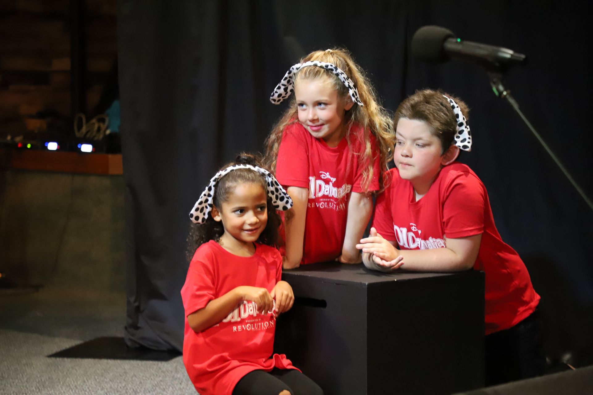 Three children wearing red shirts and headphones are posing for a picture.