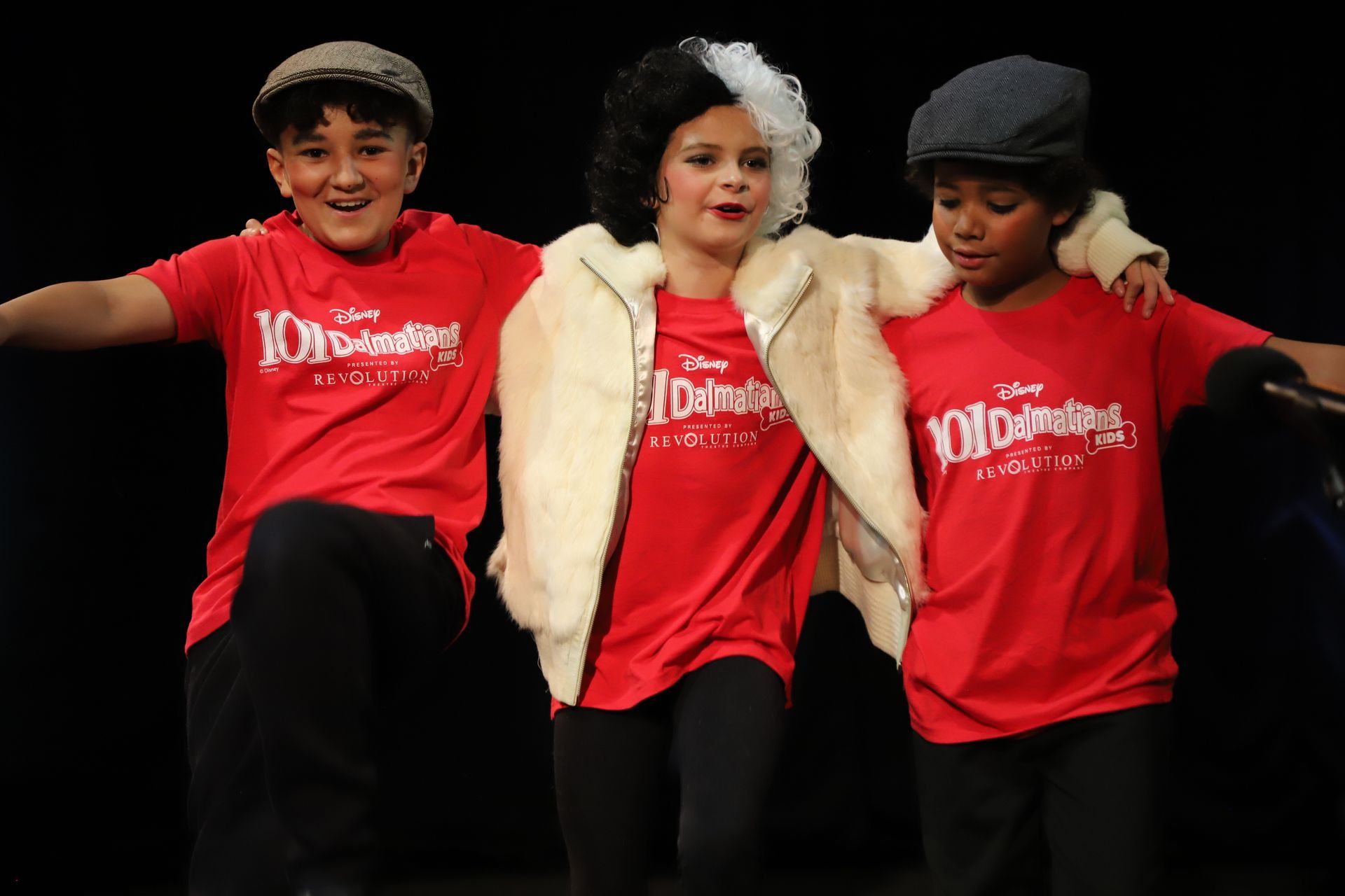 Three children are standing next to each other on a stage.