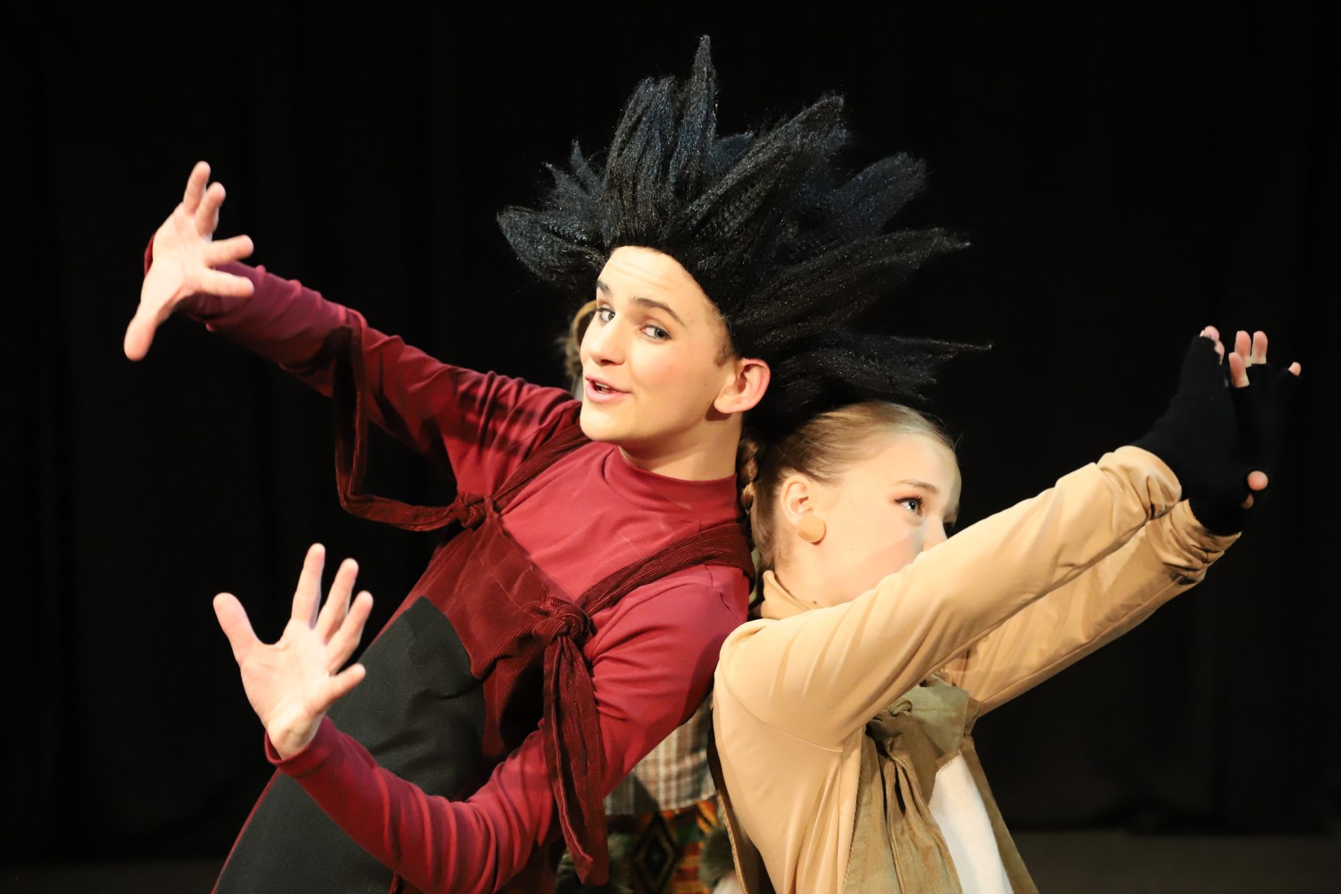 A boy and a girl are standing back to back on a stage.