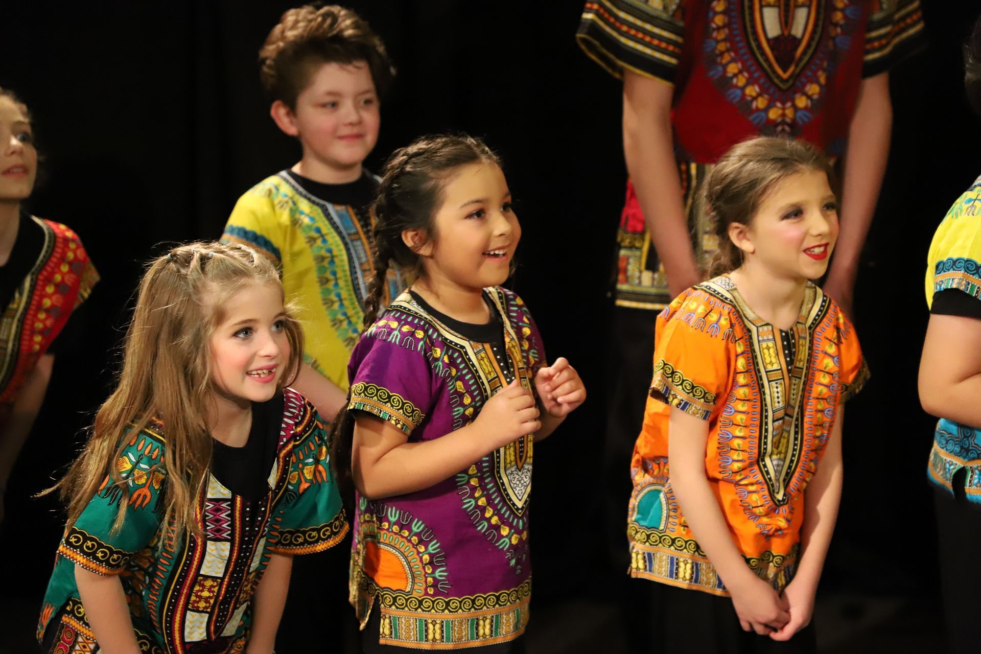 A group of children wearing colorful shirts are standing next to each other
