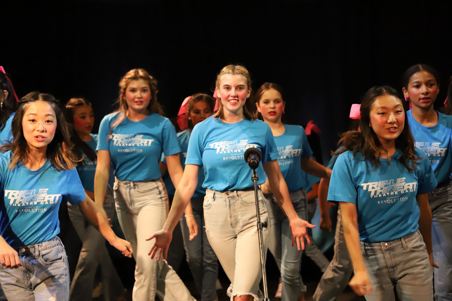 A group of young girls are dancing on a stage.