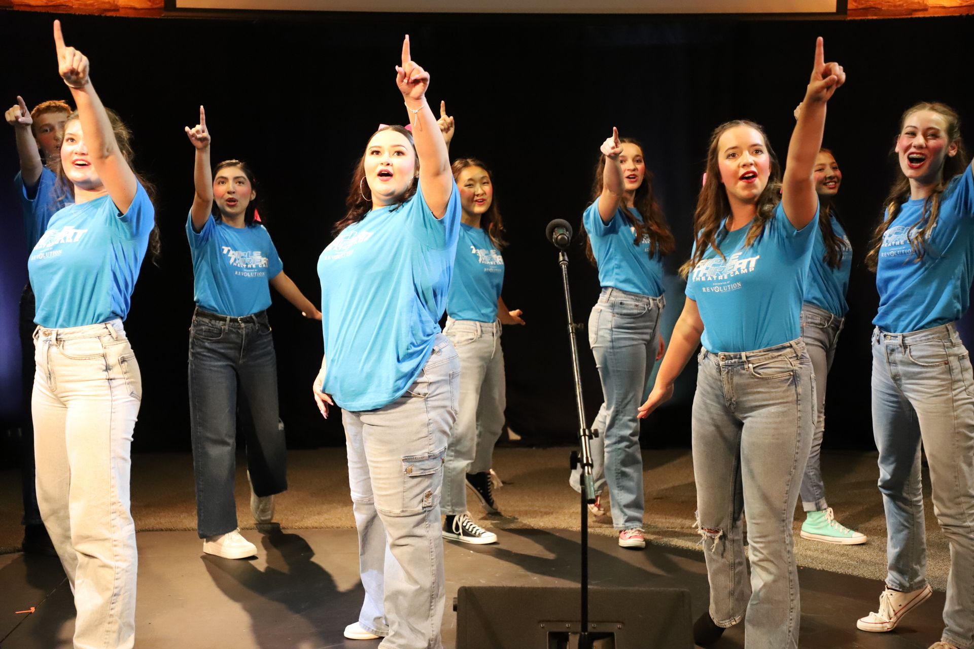 A group of young women are singing into microphones on a stage.