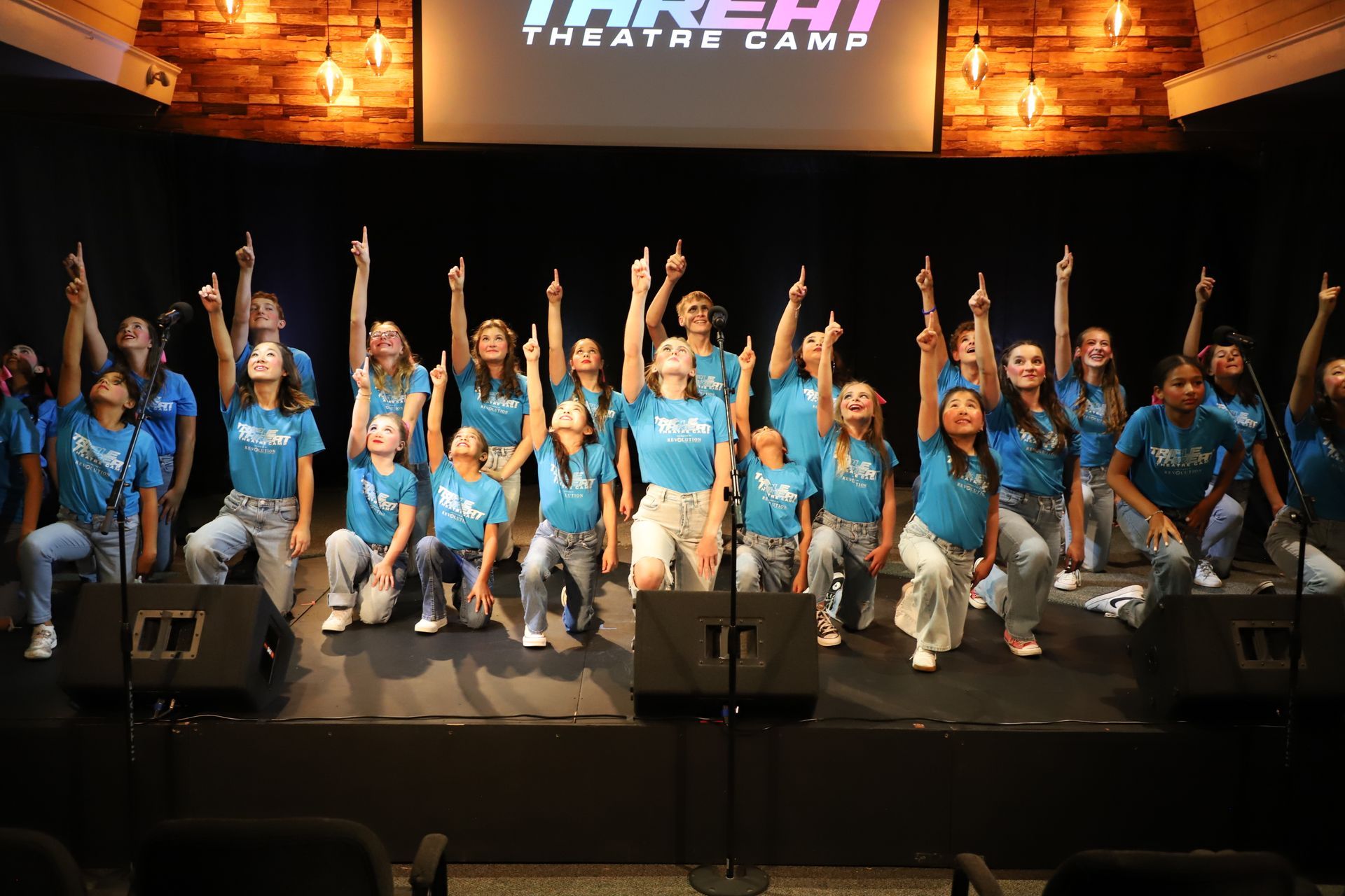 A group of people are standing on a stage with their hands in the air.