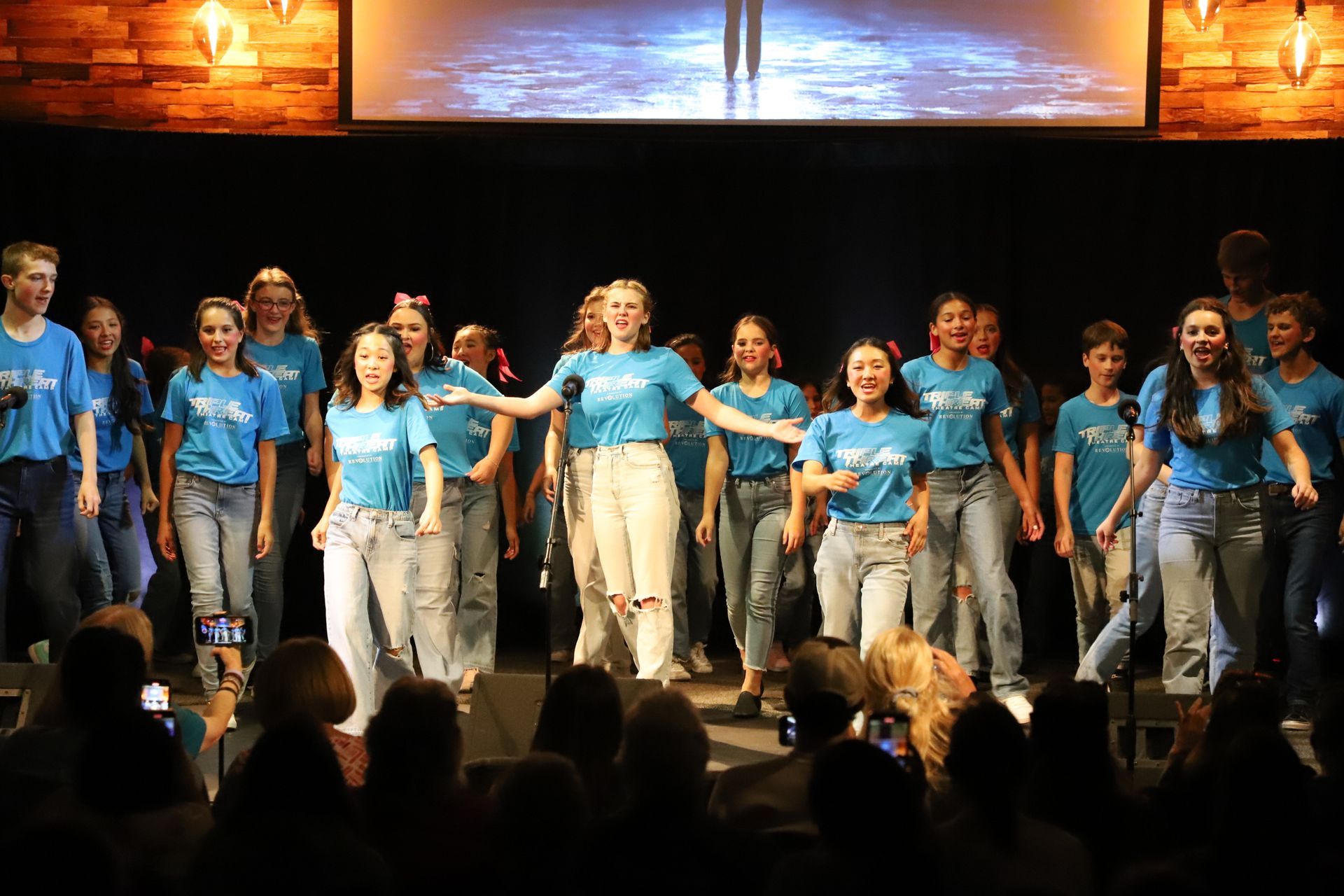 A group of young people are dancing on a stage in front of a crowd.