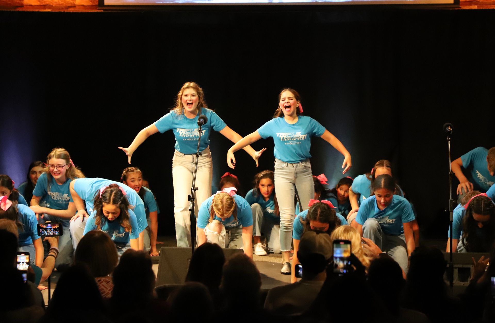 A group of young women are dancing on a stage in front of a crowd.