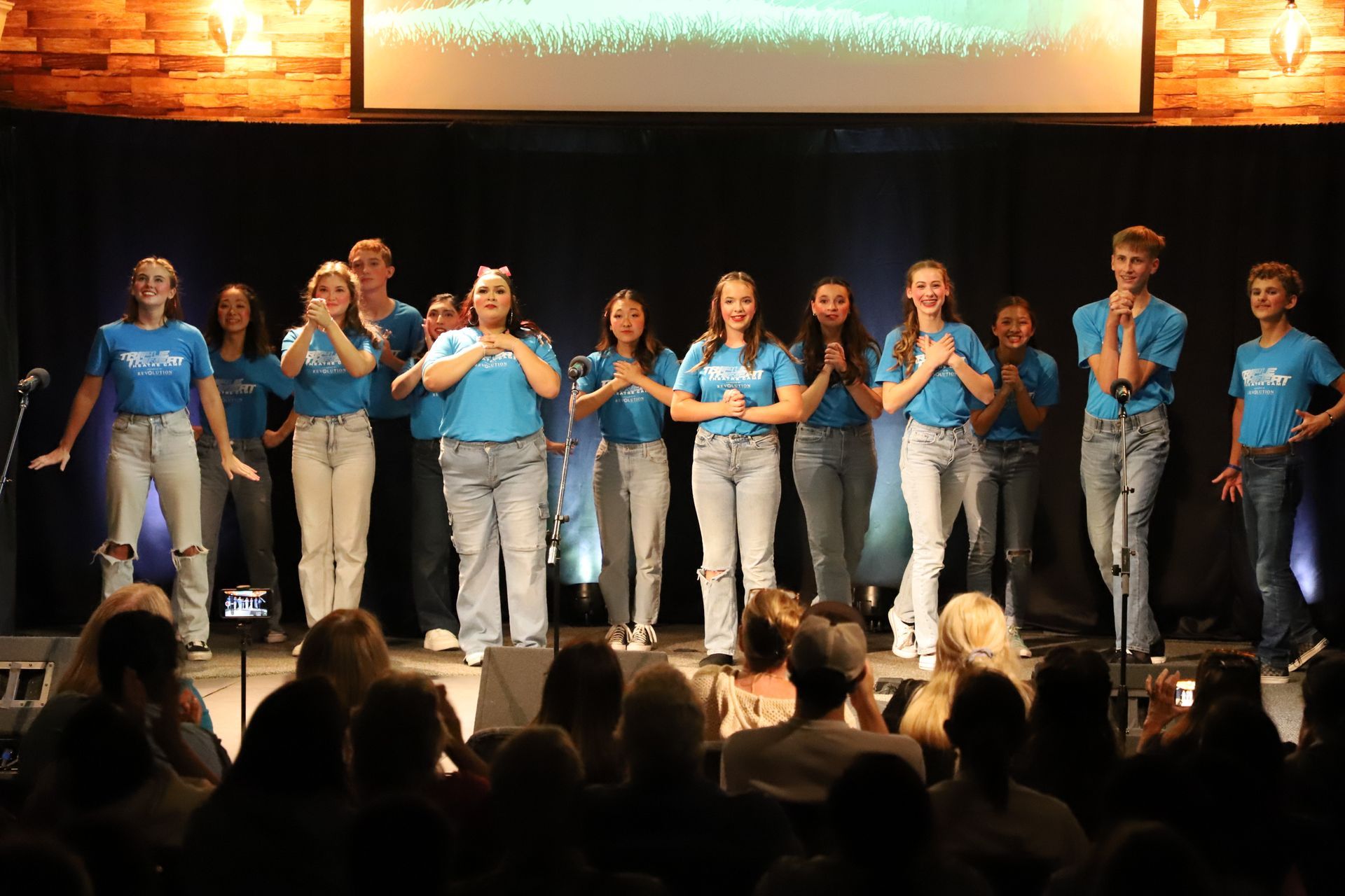 A group of people are standing on a stage in front of a crowd.