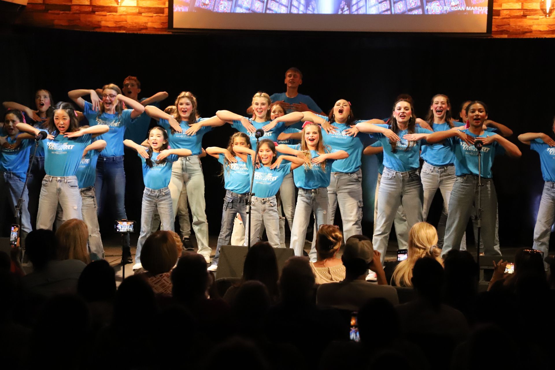 A group of young girls are dancing on a stage in front of a crowd.