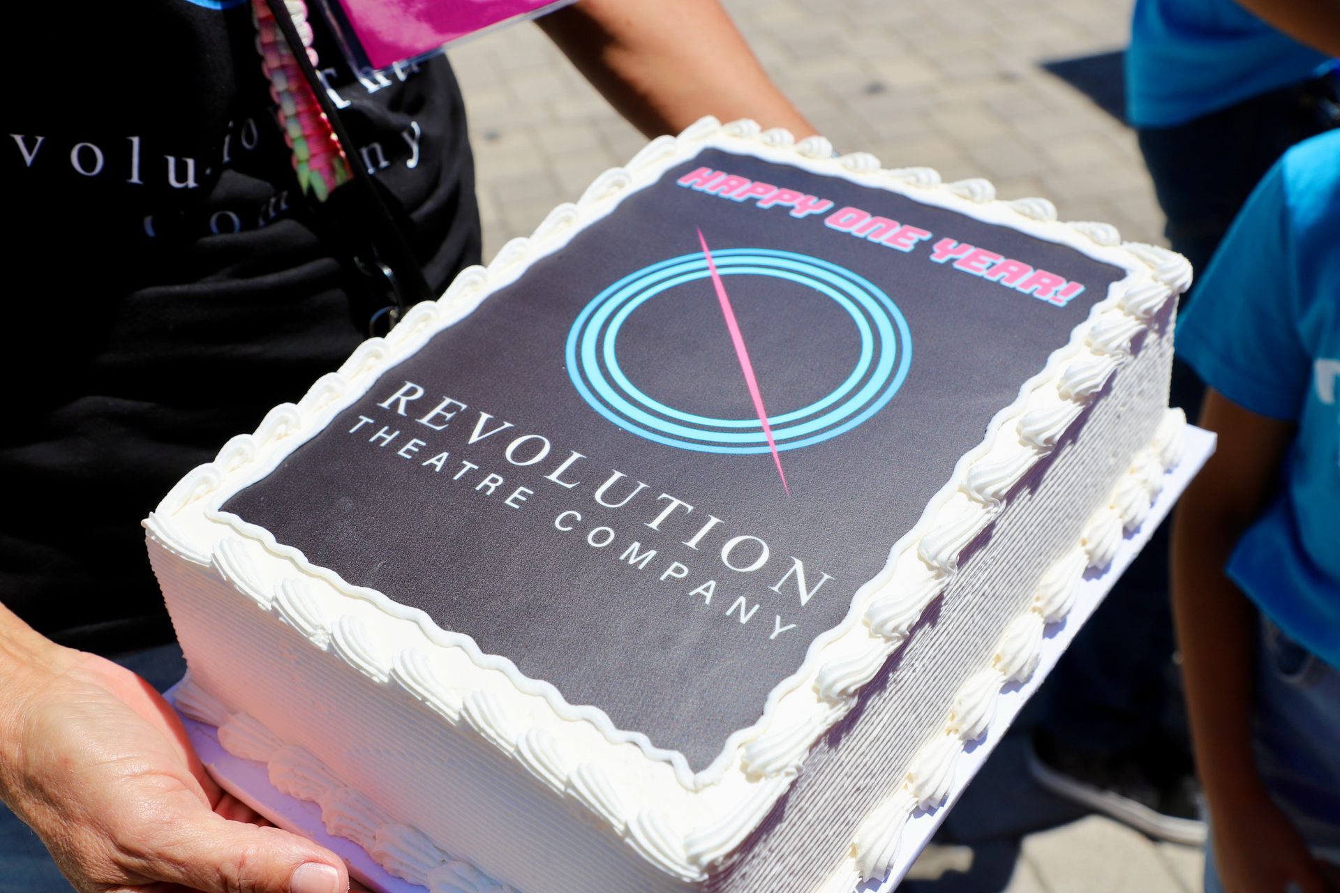 A person is holding a cake that says revolution theatre company