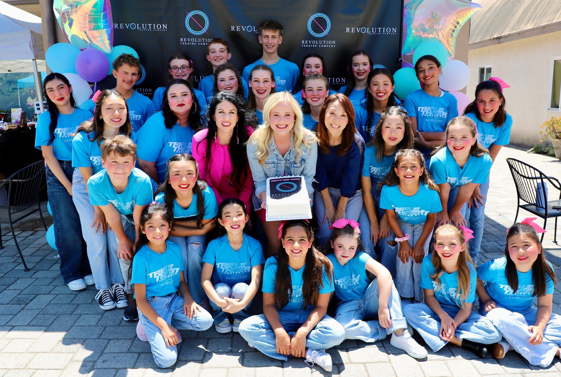 A group of children in blue shirts are posing for a picture.