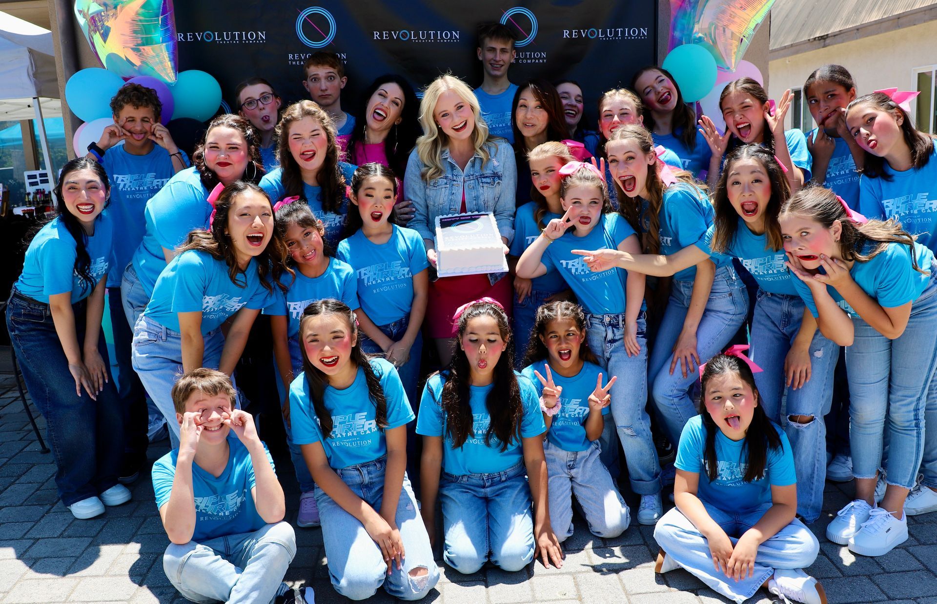 A group of young people in blue shirts are posing for a picture.