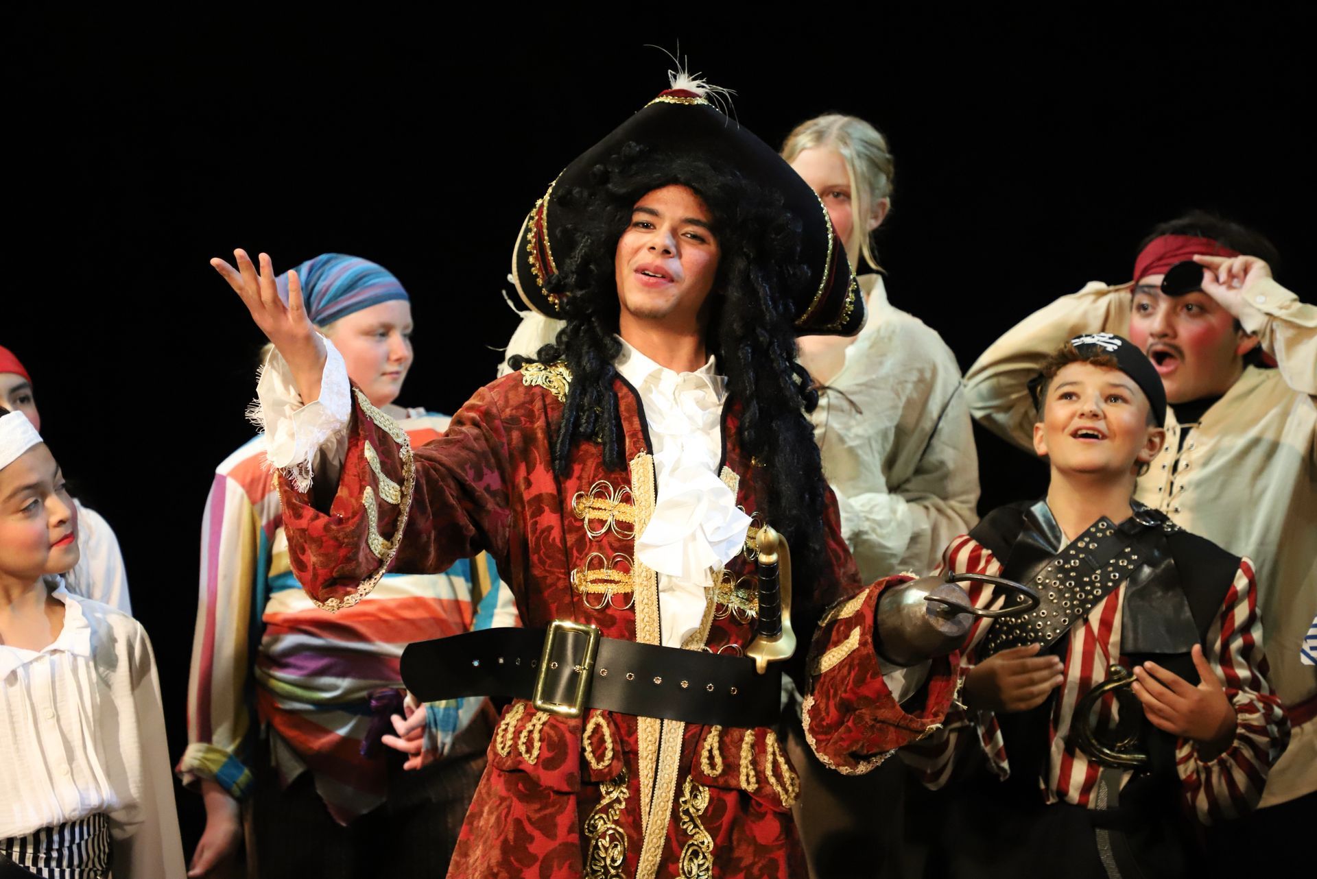 A group of children in costumes are posing for a picture on a stage.