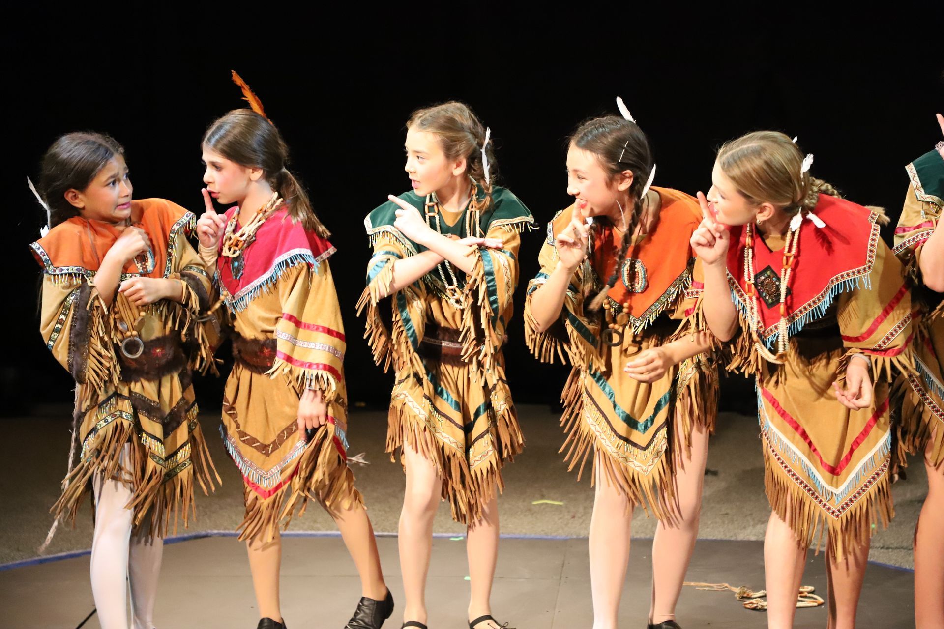 A group of girls dressed as BRAVE GIRLS are all looking at one girl in the group who looks startled