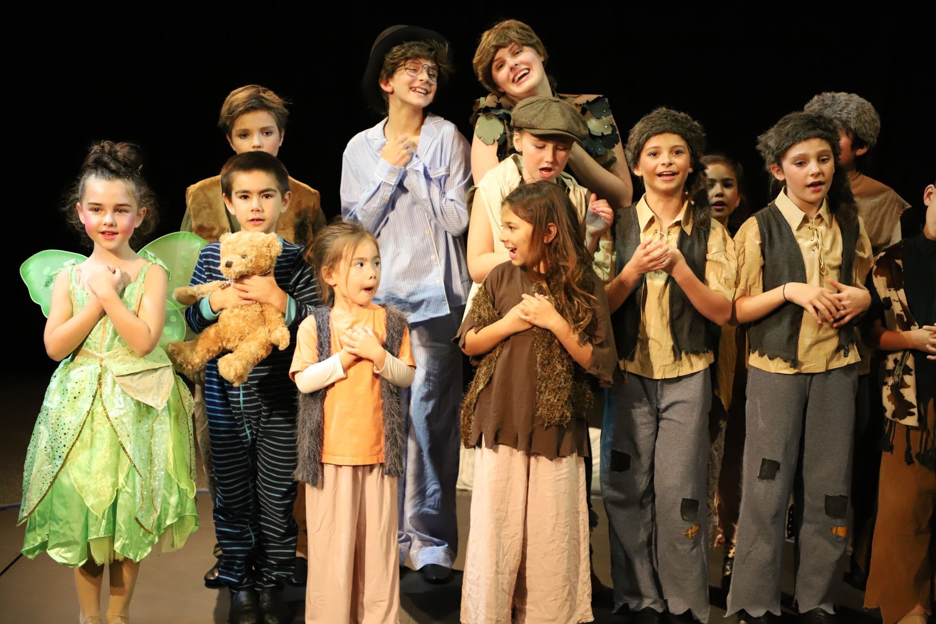 A group of children dressed in costumes are standing on a stage.