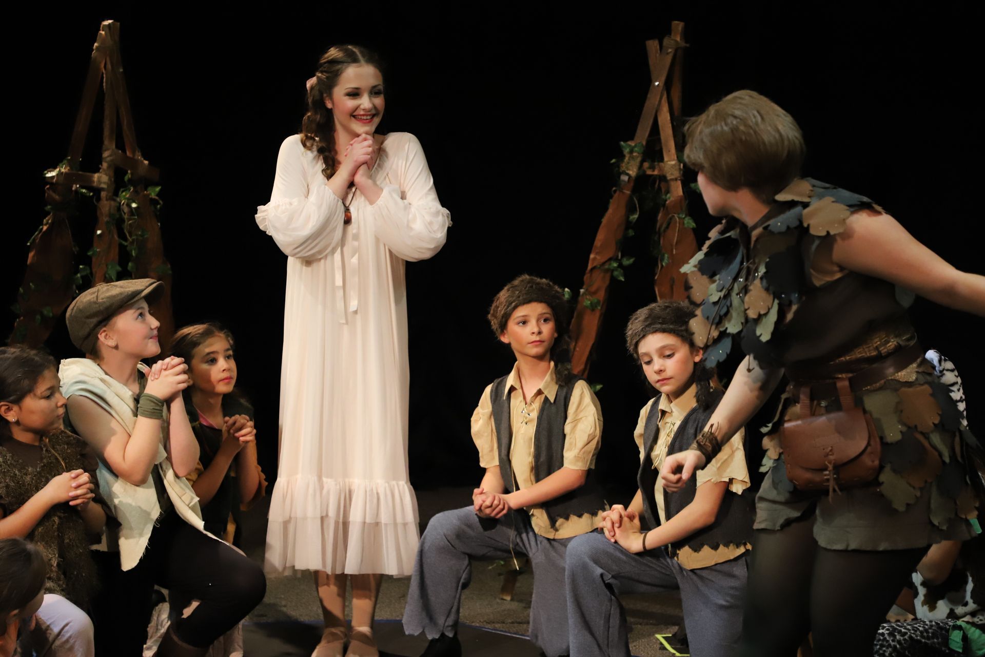 A woman in a white dress is standing in front of a group of children.