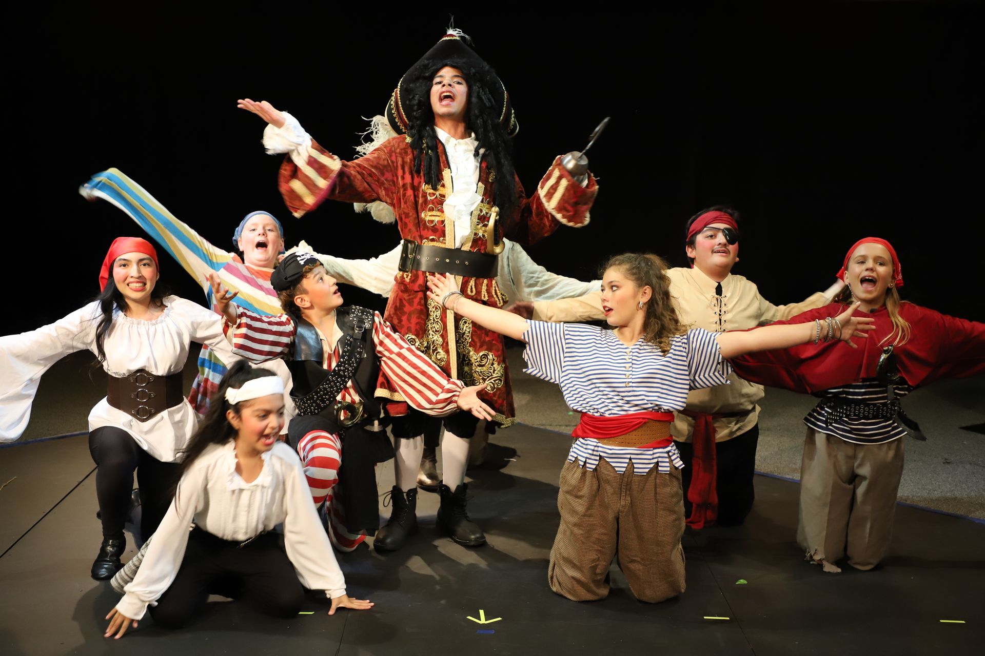 A group of people dressed in pirate costumes are dancing on a stage.