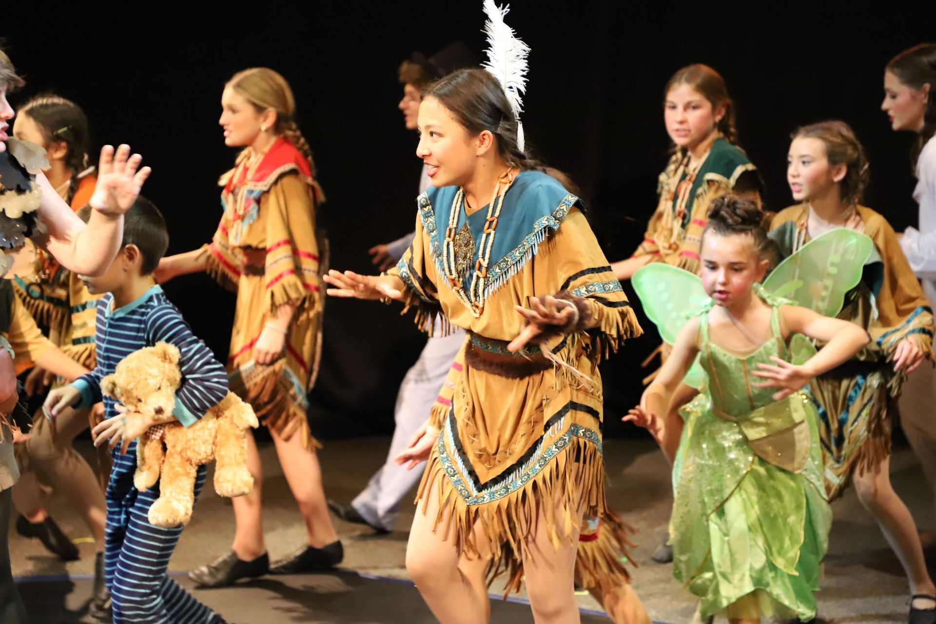 A group of children dressed in costumes are dancing on a stage.