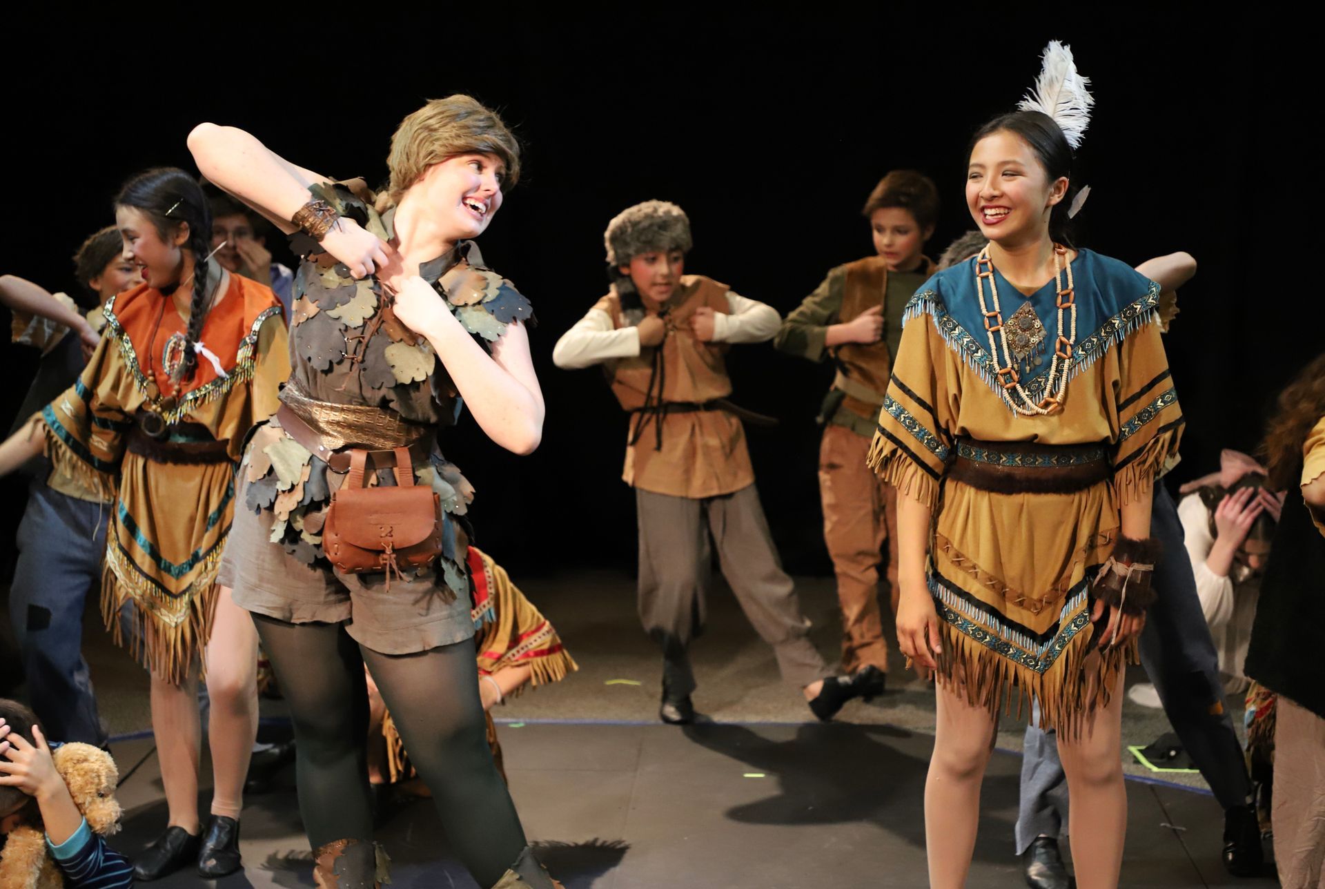 A group of people in native american costumes are dancing on a stage.