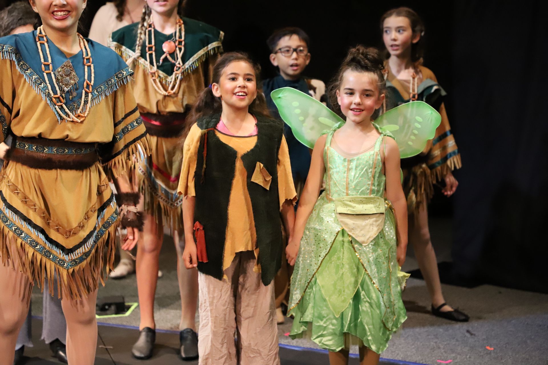A group of children dressed in costumes are standing on a stage.