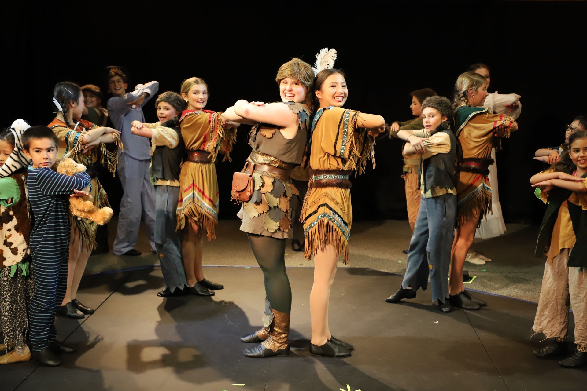 A group of children in costumes are dancing on a stage.