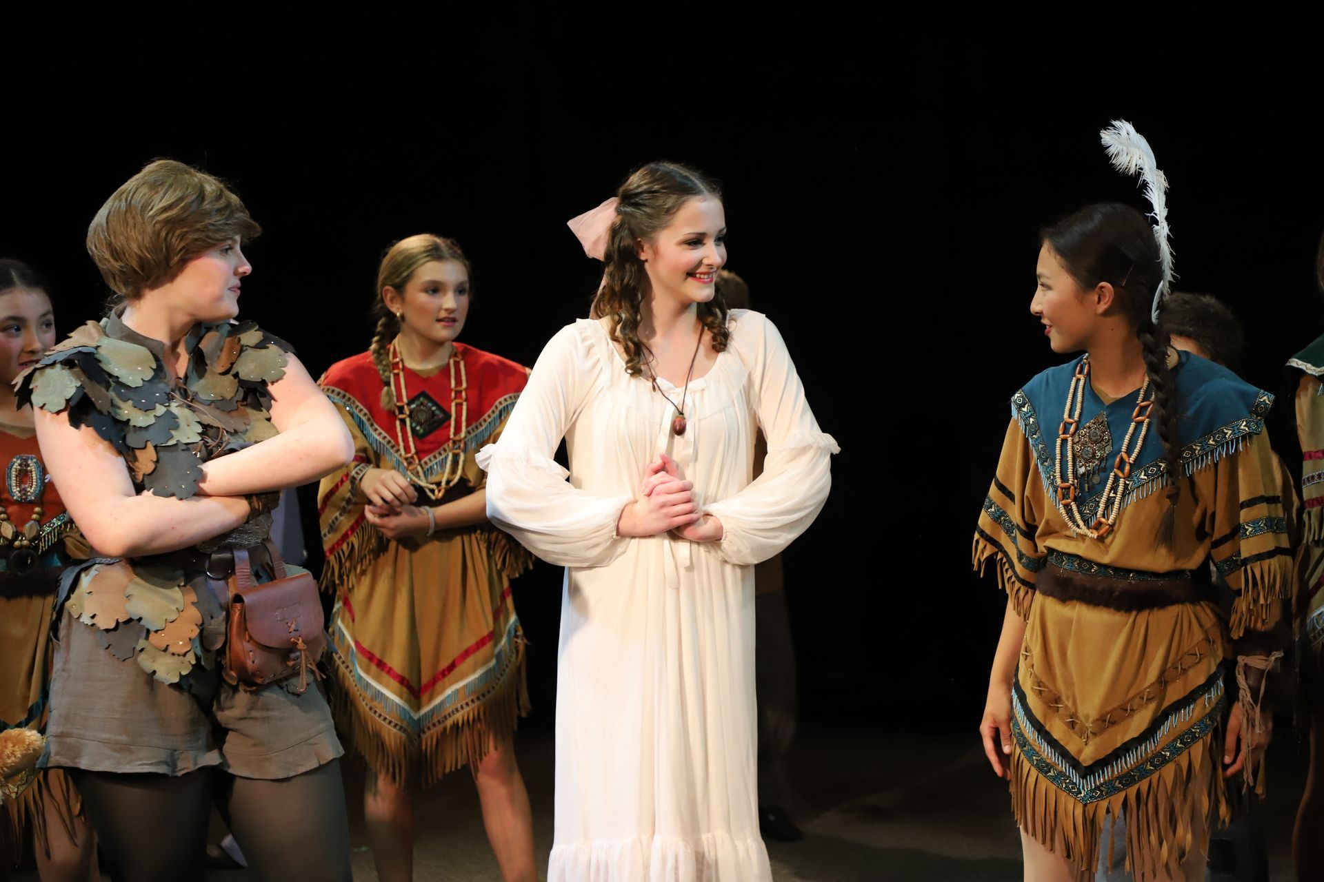 A group of people in native american costumes are standing next to each other on a stage.