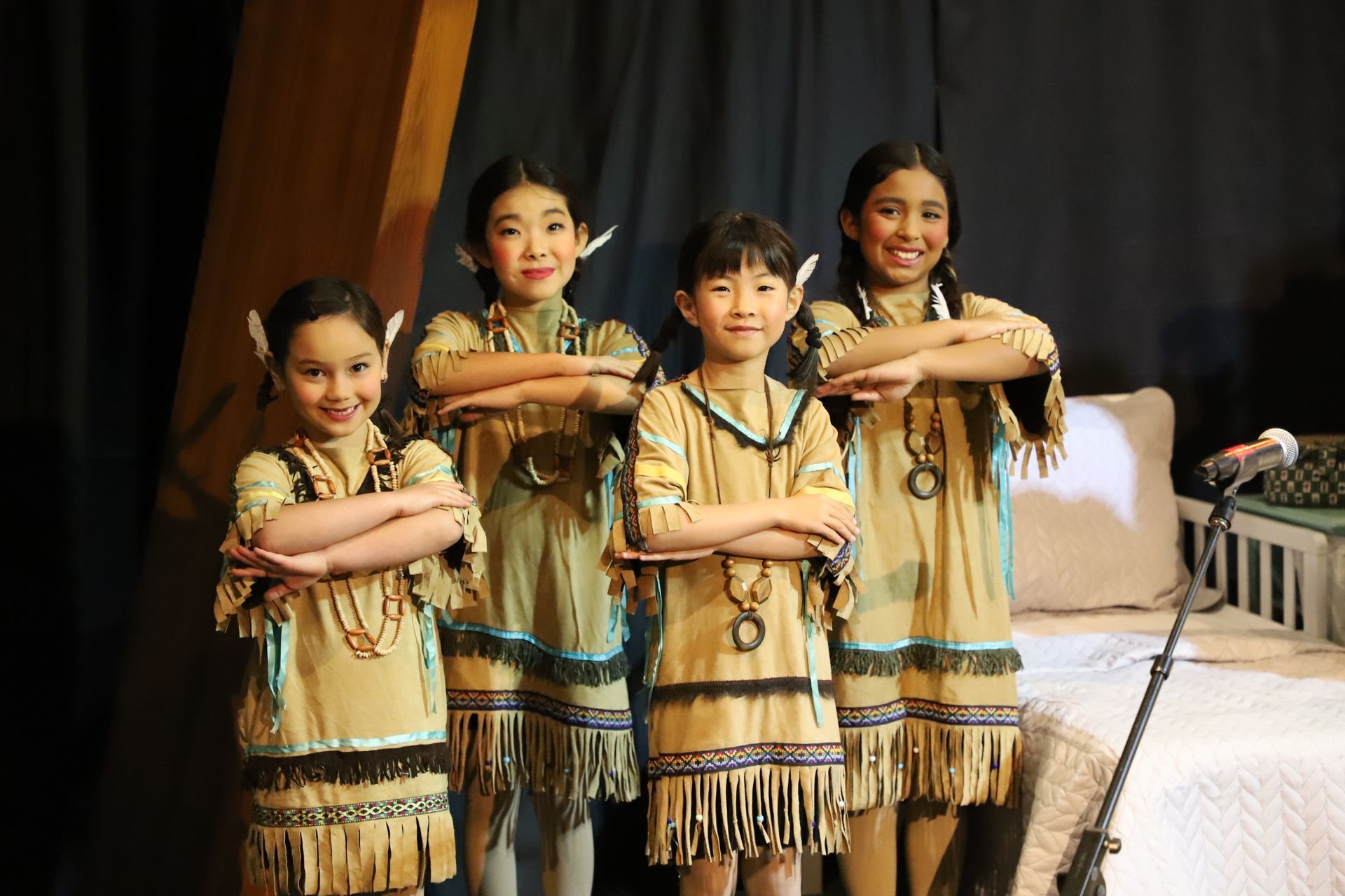 A group of young girls in native american costumes are posing for a picture.