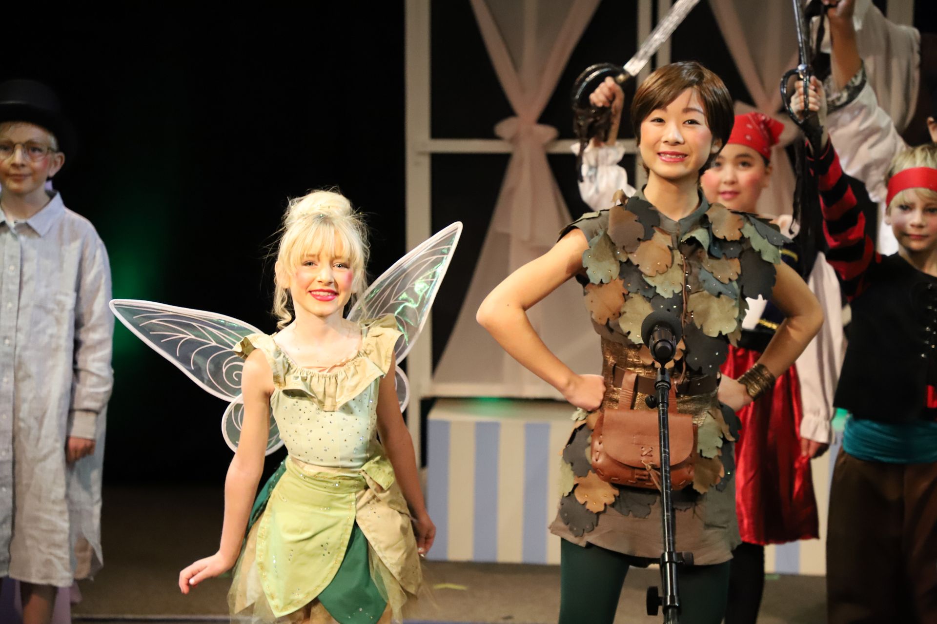 A group of children dressed as tinkerbell and peter pan on a stage.