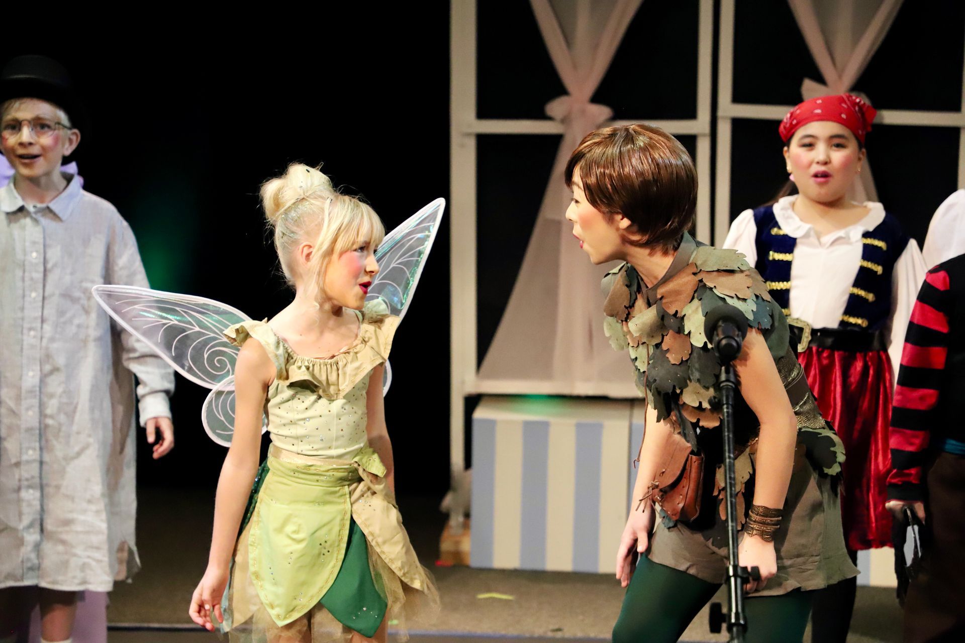 A group of children dressed as tinkerbell and peter pan on a stage.