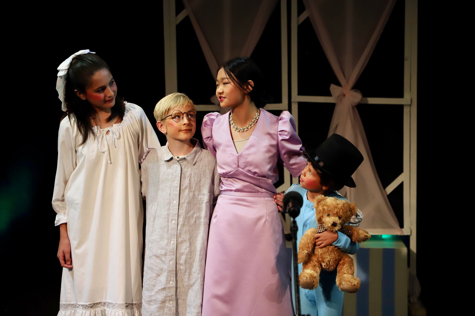 A group of children are standing next to each other on a stage.