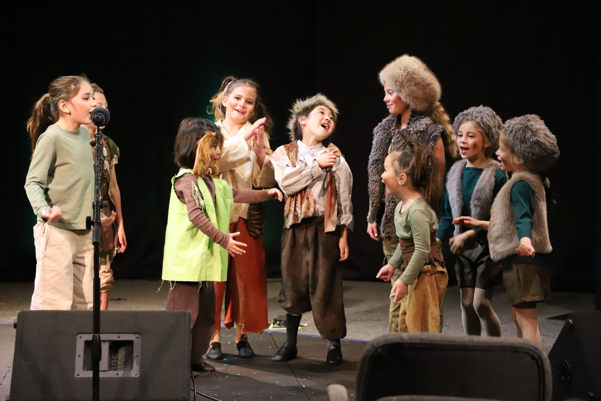 A group of children are standing in front of a microphone on a stage.