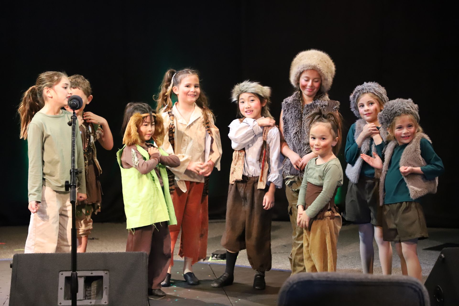 A group of children are singing into microphones on a stage.