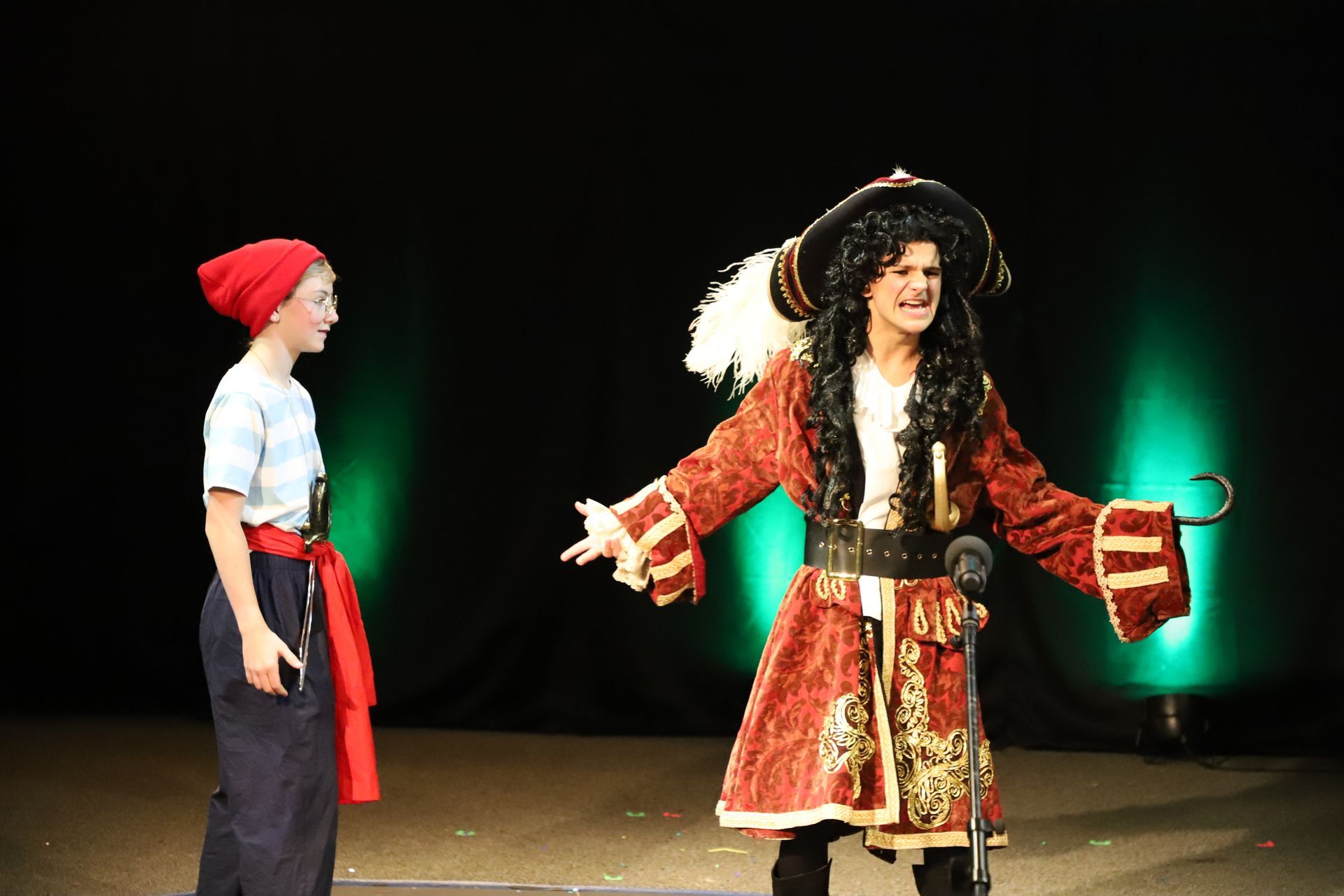 A man in a pirate costume is standing next to a girl in a red hat.