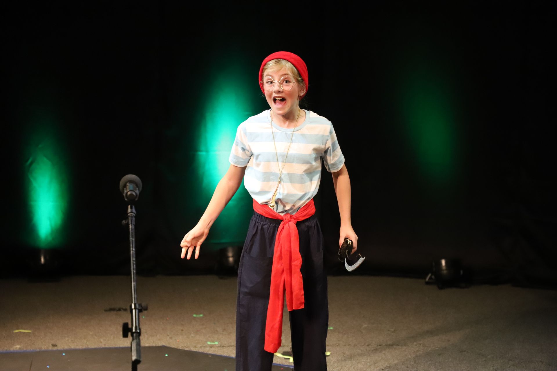 A young boy is standing in front of a microphone on a stage.