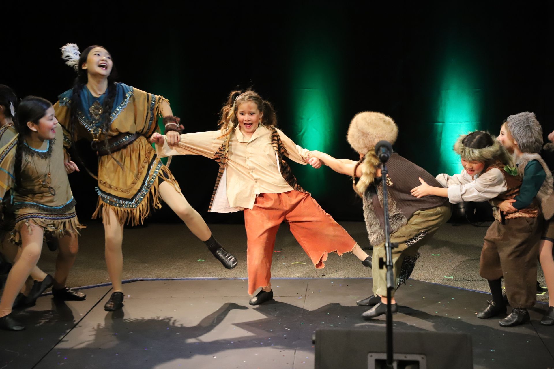 A group of children are dancing on a stage.