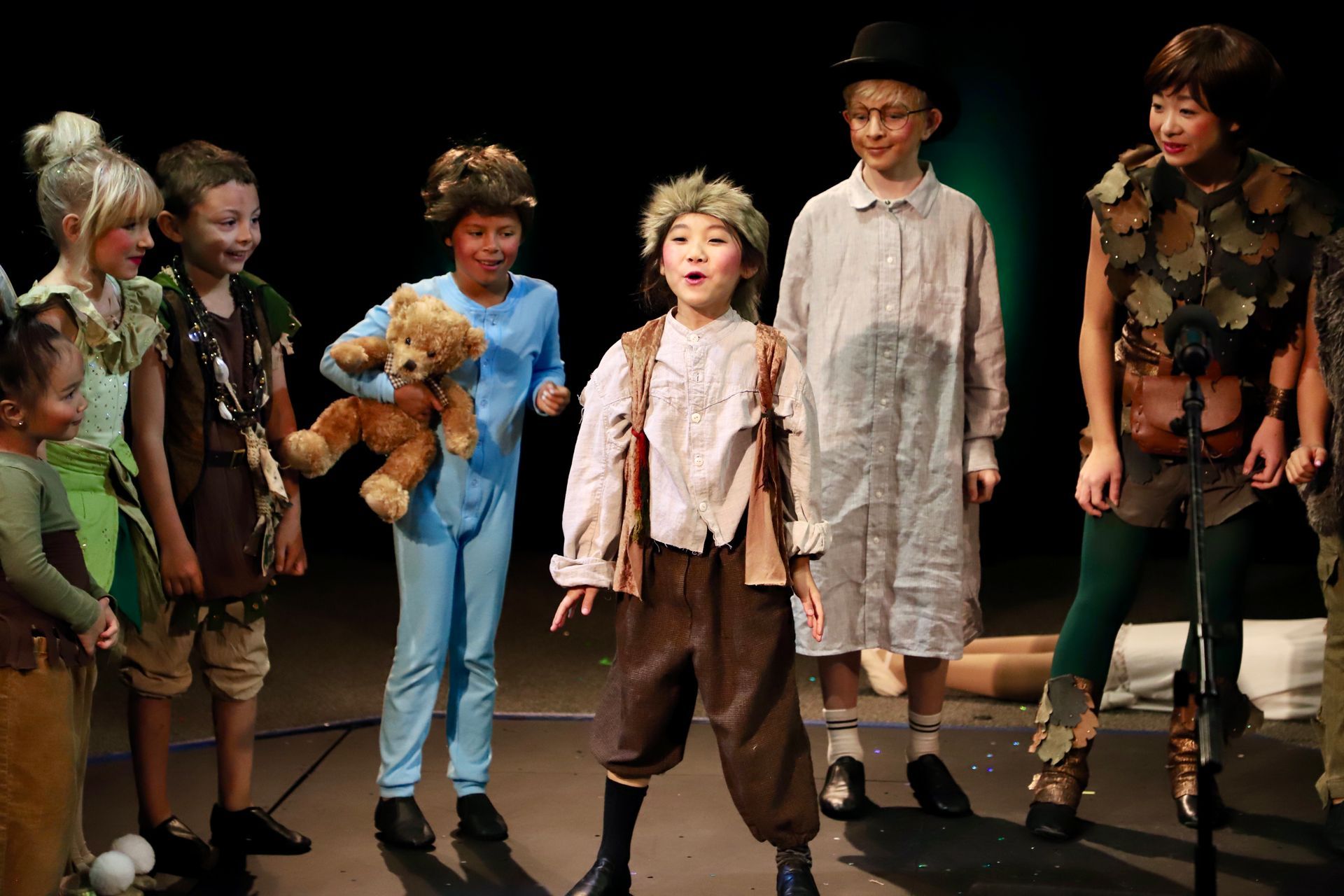 A group of children dressed as peter pan are standing on a stage.
