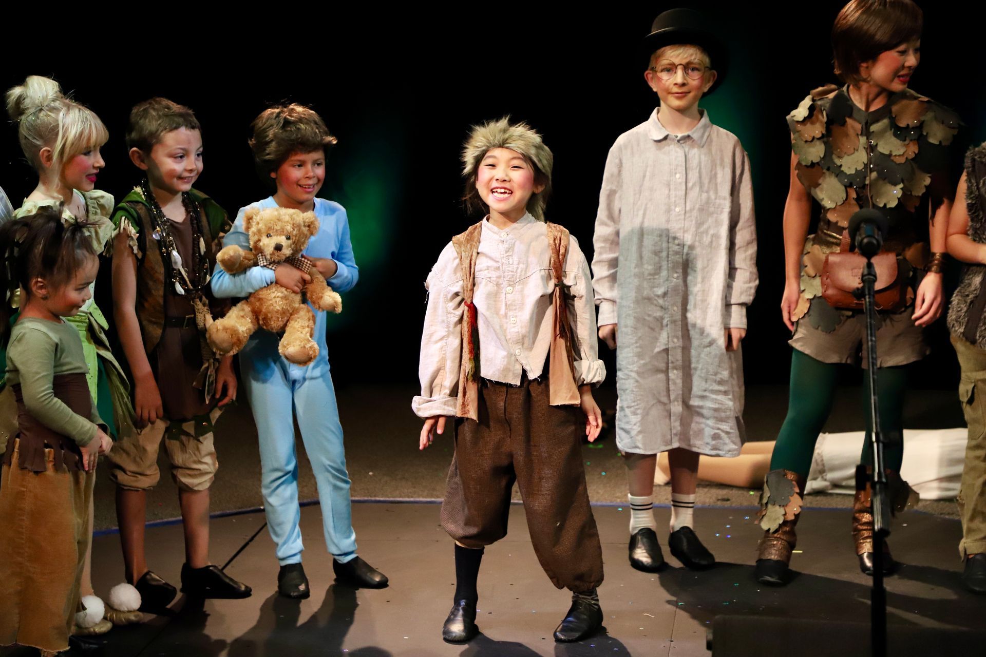 A group of children dressed in costumes are standing on a stage.