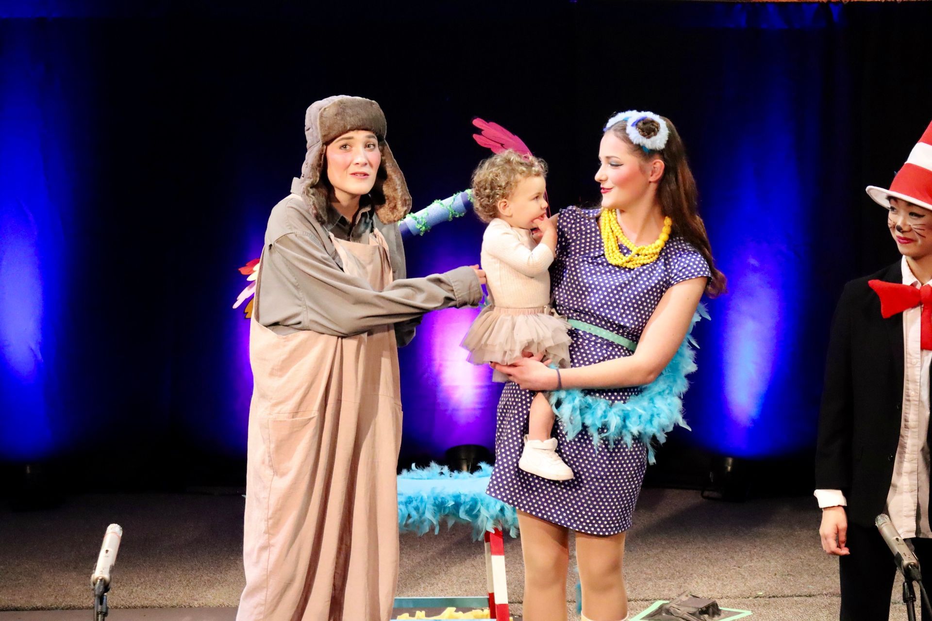 A woman in a cat in the hat costume is holding a baby